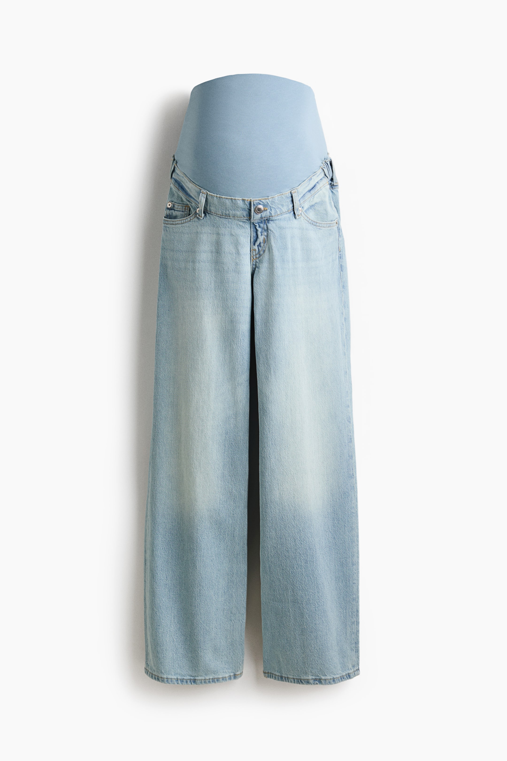 View larger image: These maternity jeans are shown from the front, featuring light blue 5-pocket cotton denim with a relaxed fit and wide, straight legs. A wide, light blue jersey panel extends over the tummy, with covered elastic creating gathers at the sides where the denim meets the jersey. A faux fly and button appear at the front.