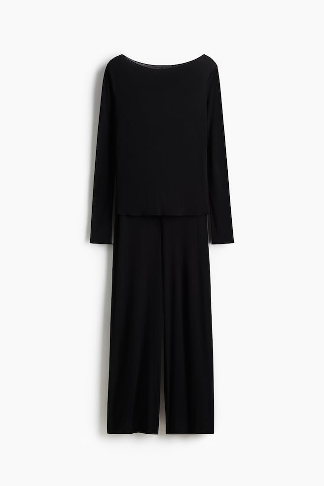 Pyjamas are featuring a long-sleeved top and wide-leg trousers in black ribbed jersey. The top is displaying a boat neckline and a fitted silhouette. - 1