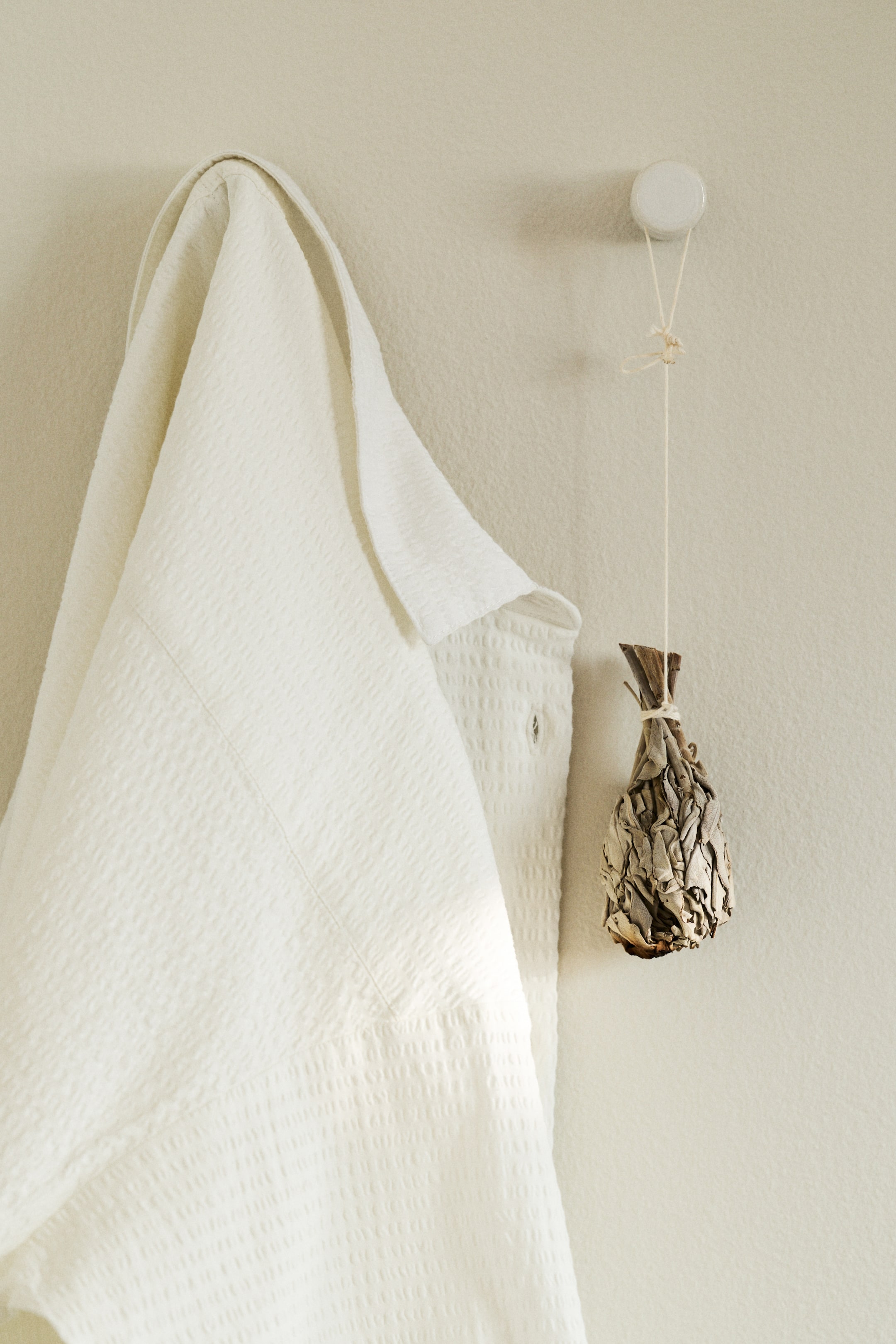 View larger image: A white waffle-weave robe is hanging, showcasing its textured fabric, a visible collar, and a partially visible front pocket.