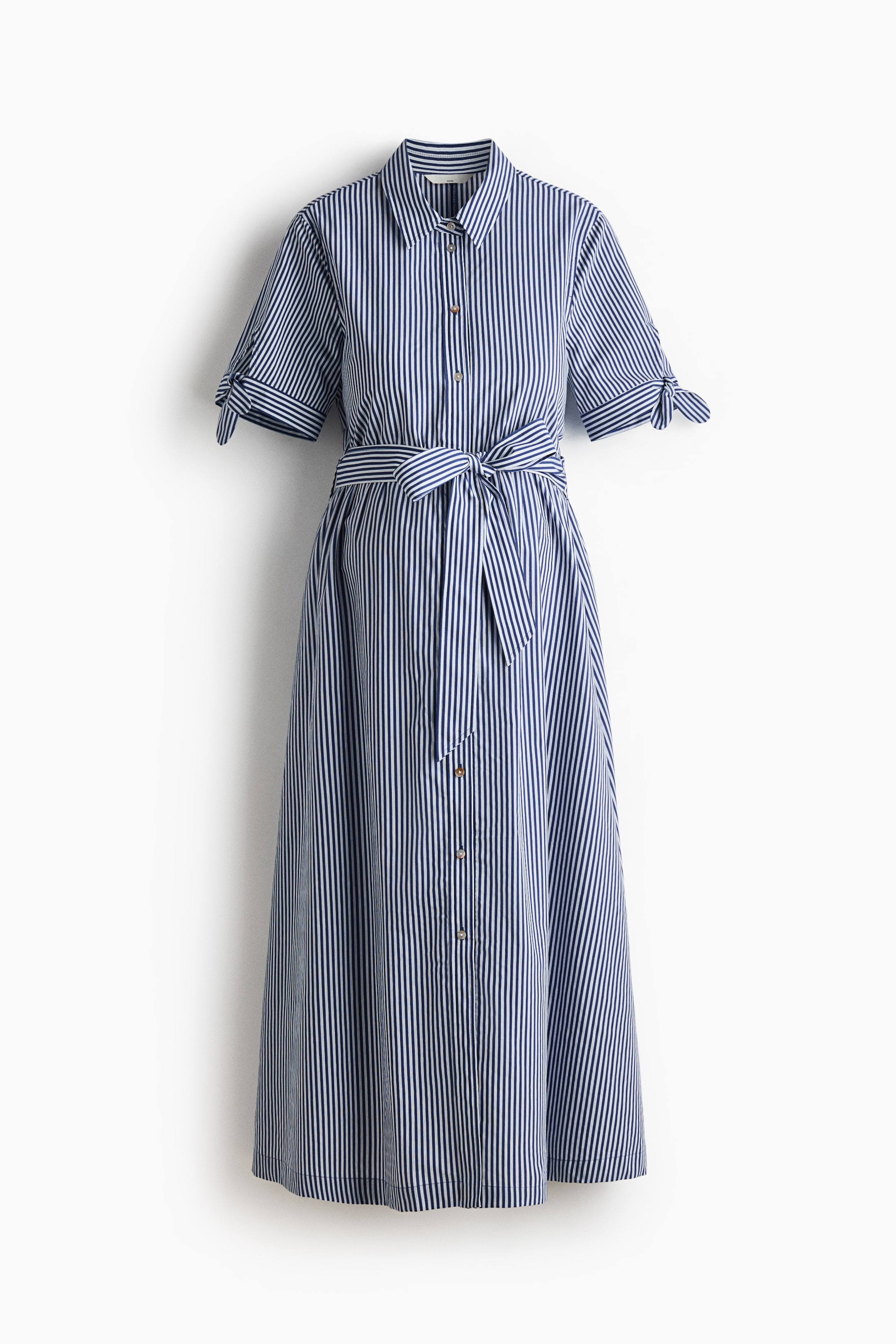 View larger image: A calf-length dress in blue and white vertical stripes is showcasing its front, featuring a collar, buttons down the front, and short sleeves with slits and wide ties at the cuffs. A detachable tie belt is cinching the gathered waist, leading to a gently flared skirt.