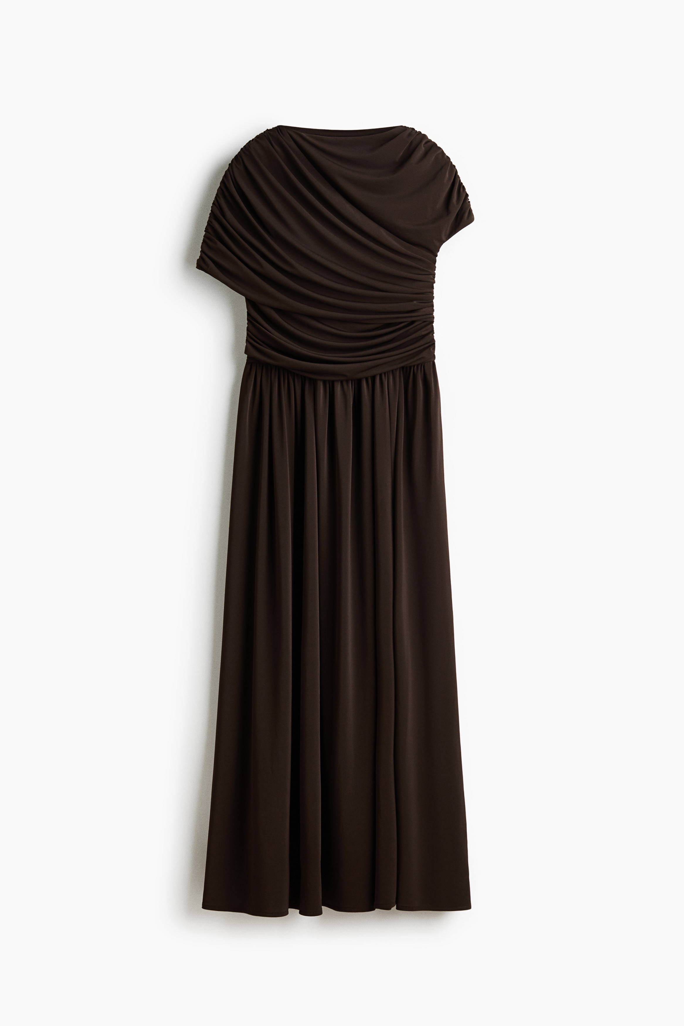 The model is wearing a dark brown stretch jersey dress featuring a high neckline, an asymmetrical draped sleeve panel on one side, and a short sleeve on the other. The dress has a fitted bodice with gathered draping throughout, a defined gathered waist, and a flared skirt.
