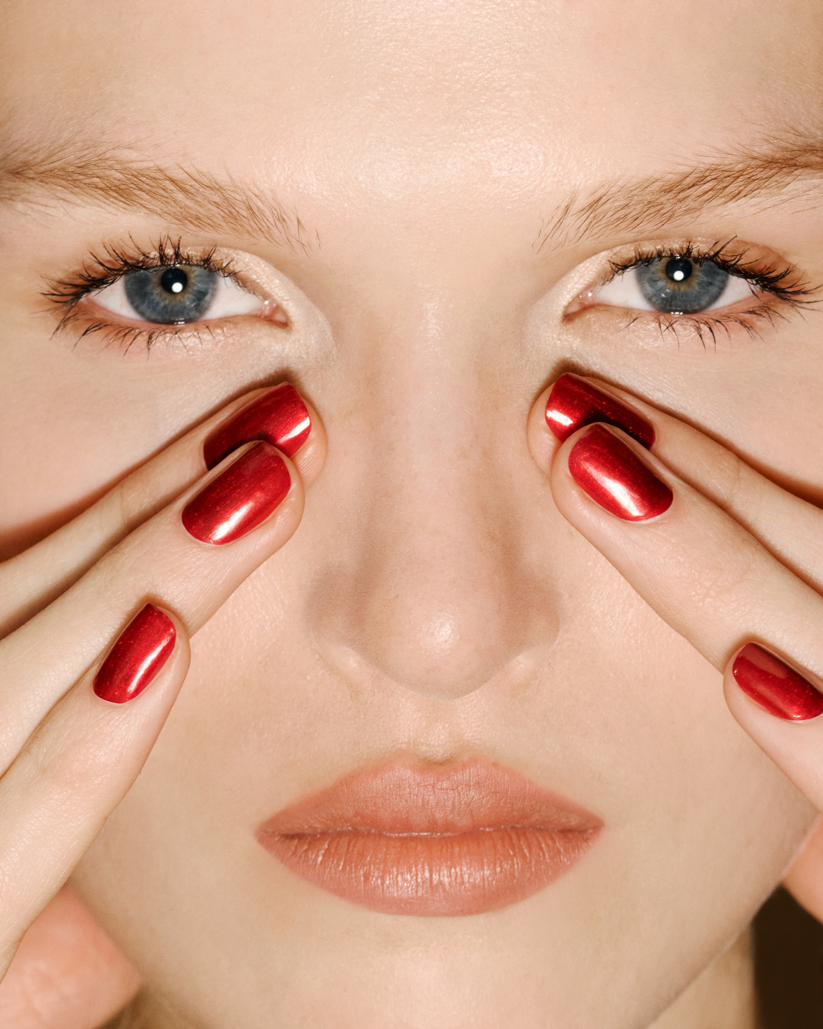 Un flacon de vernis Ã  ongles est posÃ© debout, face avant, mettant en valeur une base carrÃ©e transparente en verre remplie dâun vernis rouge mÃ©tallique scintillant. Le flacon prÃ©sente un large capuchon sphÃ©rique argentÃ© rÃ©flÃ©chissant et affiche un marquage dorÃ© sur la face avant.