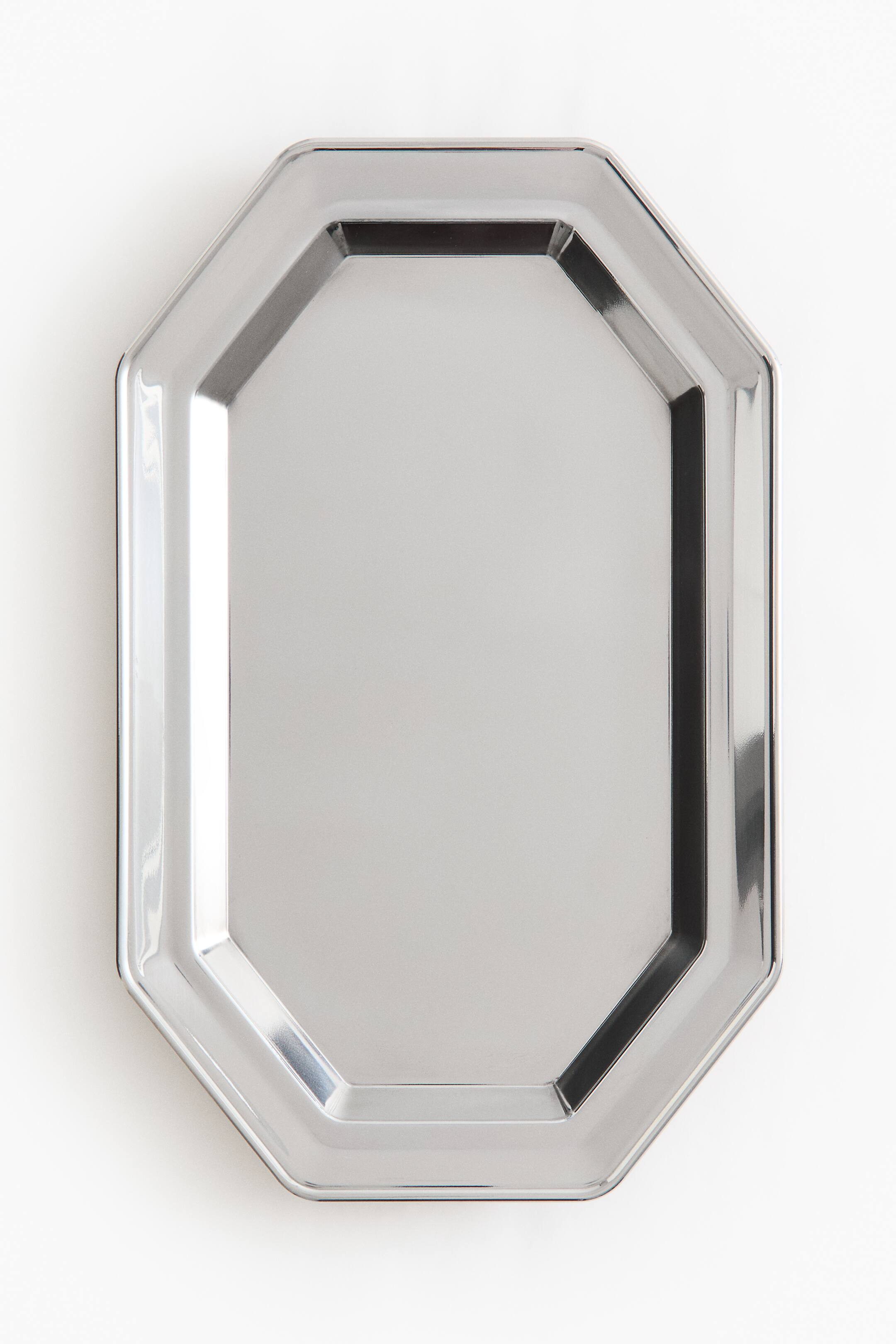 View larger image: A silver-coloured metallic tray displays a front-facing, elongated octagonal shape with a highly polished, reflective finish. The tray features a raised, multi-angled rim surrounding a flat, smooth central surface.