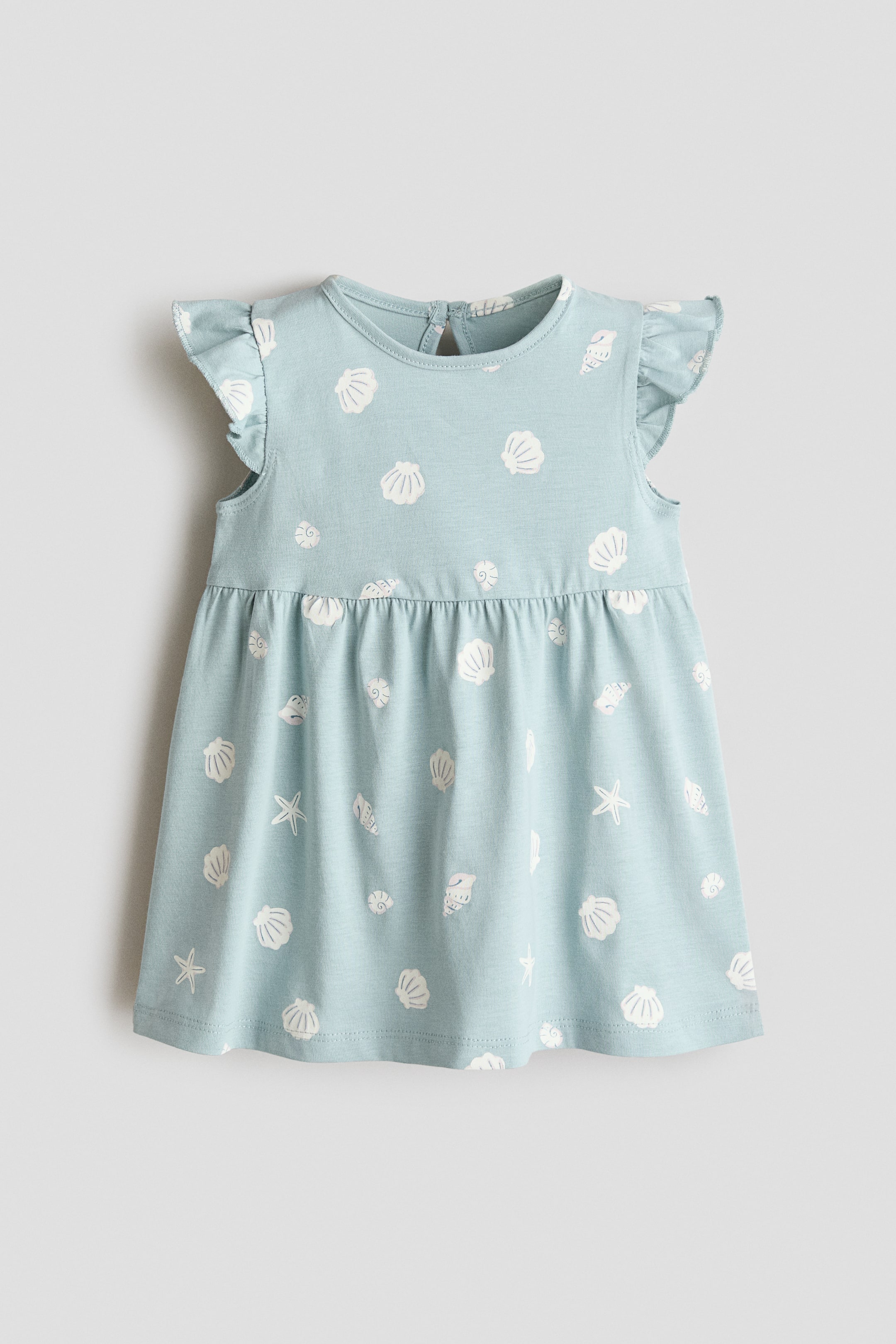 View larger image: This light blue printed cotton jersey dress showcases its front adorned with white seashells and starfish. It features a round neckline, flutter sleeves, a keyhole opening with a button at the back, gathers at the waist, and a flared skirt.