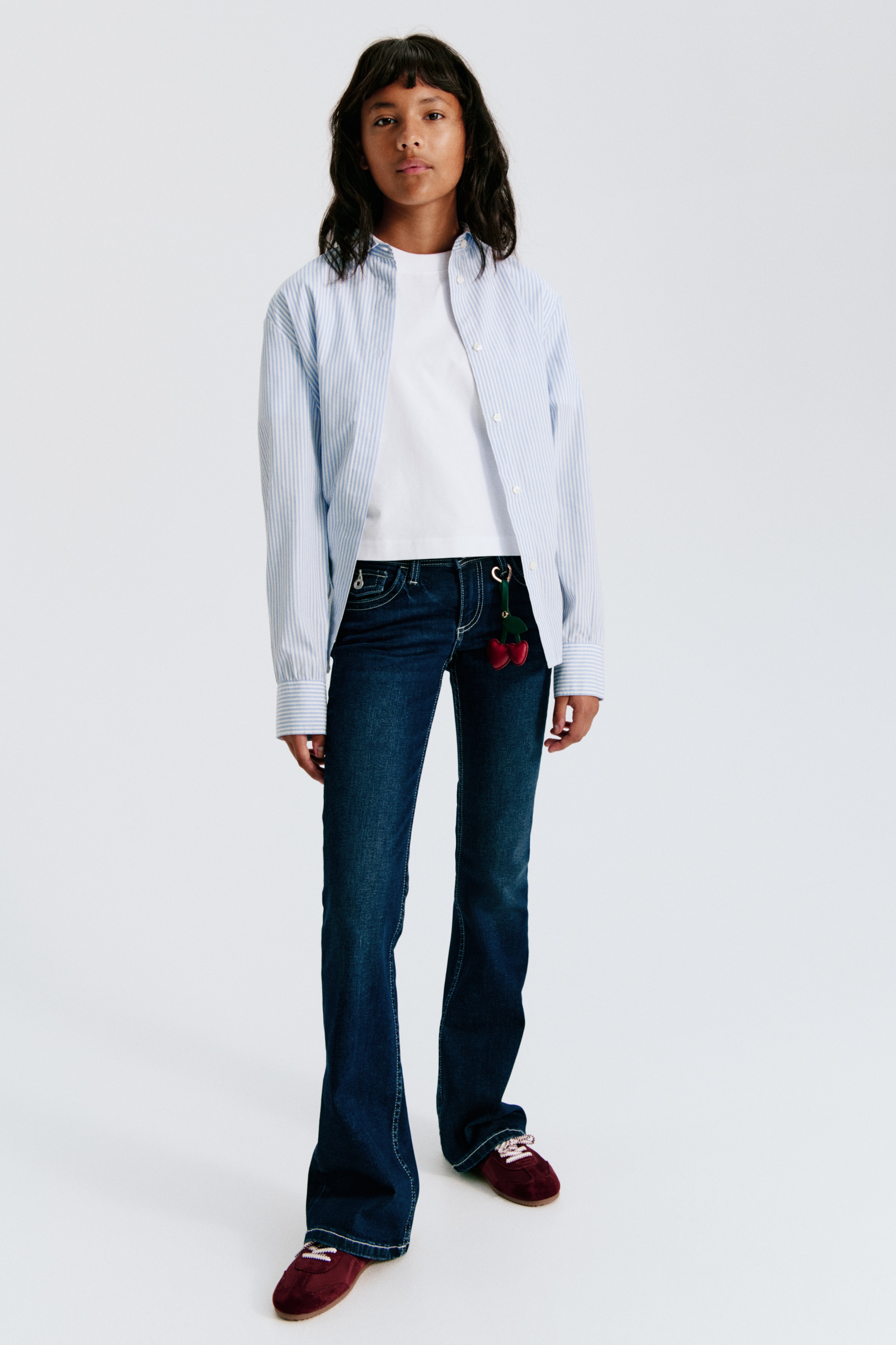 Jeans bootcut in indaco scuro sono distesi in posizione piatta, mostrando una vista frontale con cuciture a contrasto leggero, due tasche anteriori a cucchiaio, una tasca portamonete e una chiusura con bottone argentato in vita.