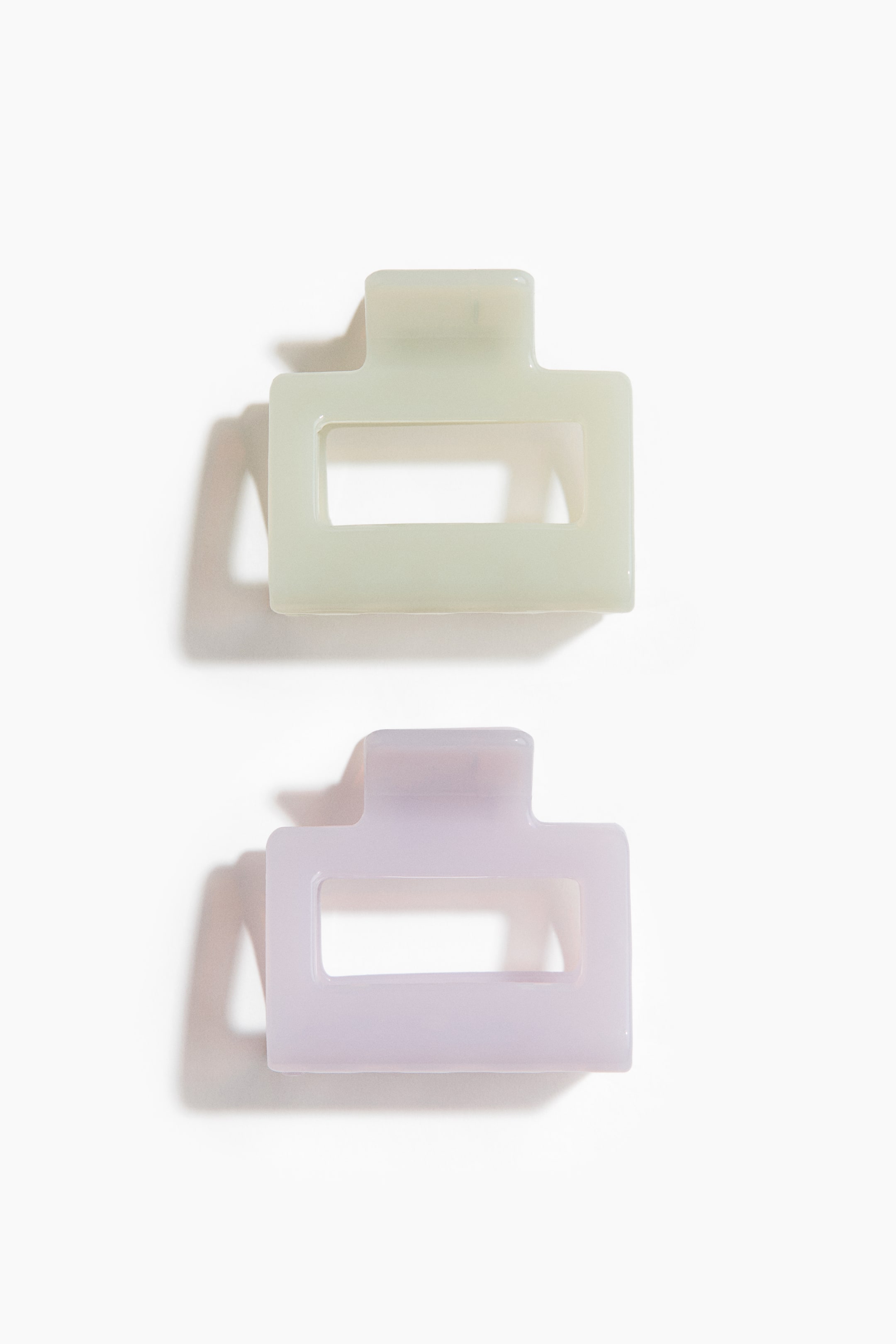 Voir une image plus grande: Deux pinces à cheveux rectangulaires en plastique, chacune mesurant 5 cm de longueur, sont exposées face vers le haut, l'une en vert sauge clair et l'autre en lavande douce, toutes deux dotées d'une découpe rectangulaire dans leur corps principal.