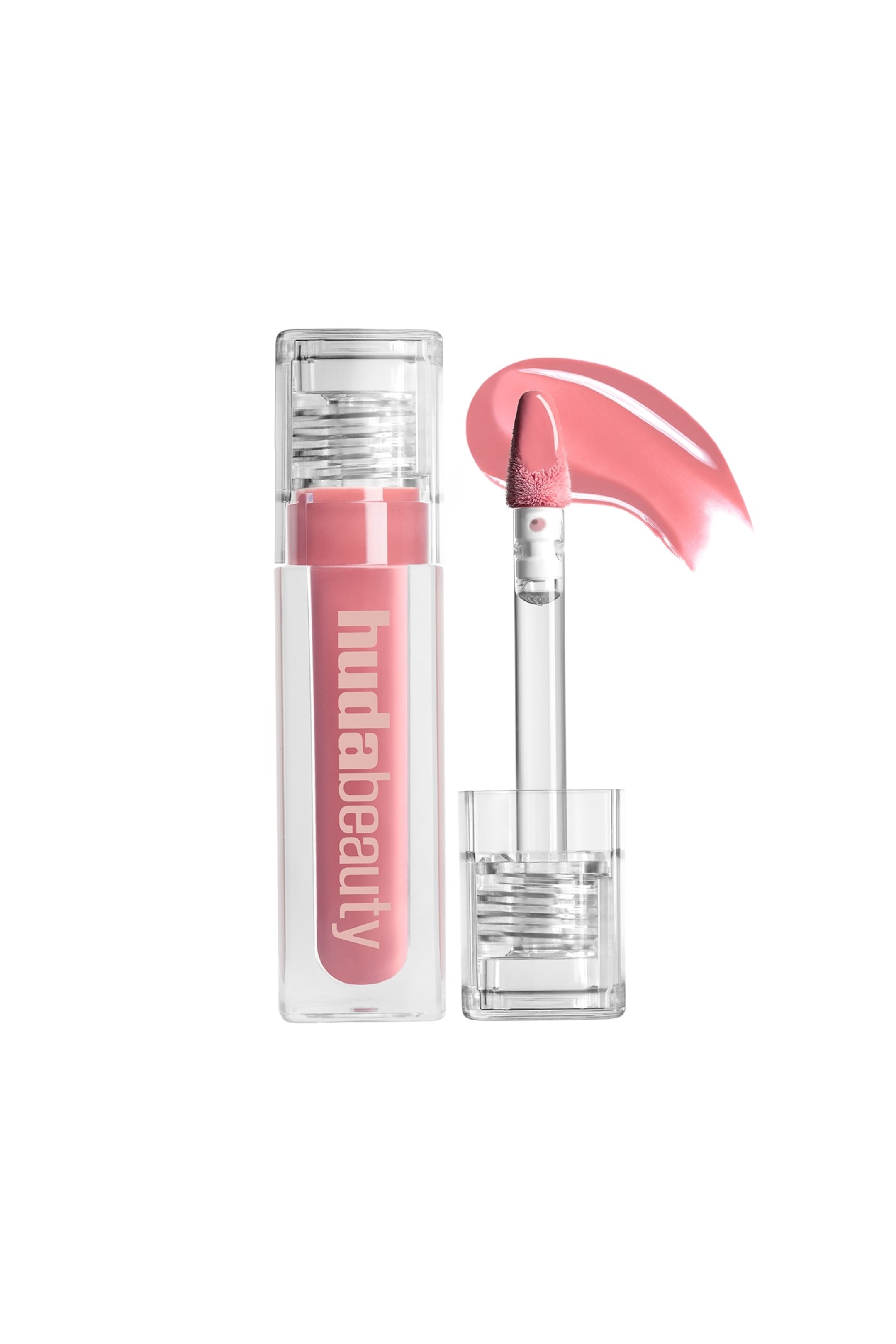 Näytä suurempi kuva: Huulikiilto, jossa on kirkas suorakulmainen putkilo, täytetty vaaleanpunaisella kiillolla ja kirkas uurrettu korkki, jonka sivulla näkyy pystysuunnassa "hudabeauty"-teksti. Kirkas applikaattoripuikko, jossa on vaaleanpunainen, laakamuotoinen kärki, on sijoitettu oikealle, näyttäen kaarevan näytteen kiillosta, kun sen pohja lepää kirkkaassa, uurretussa osassa.