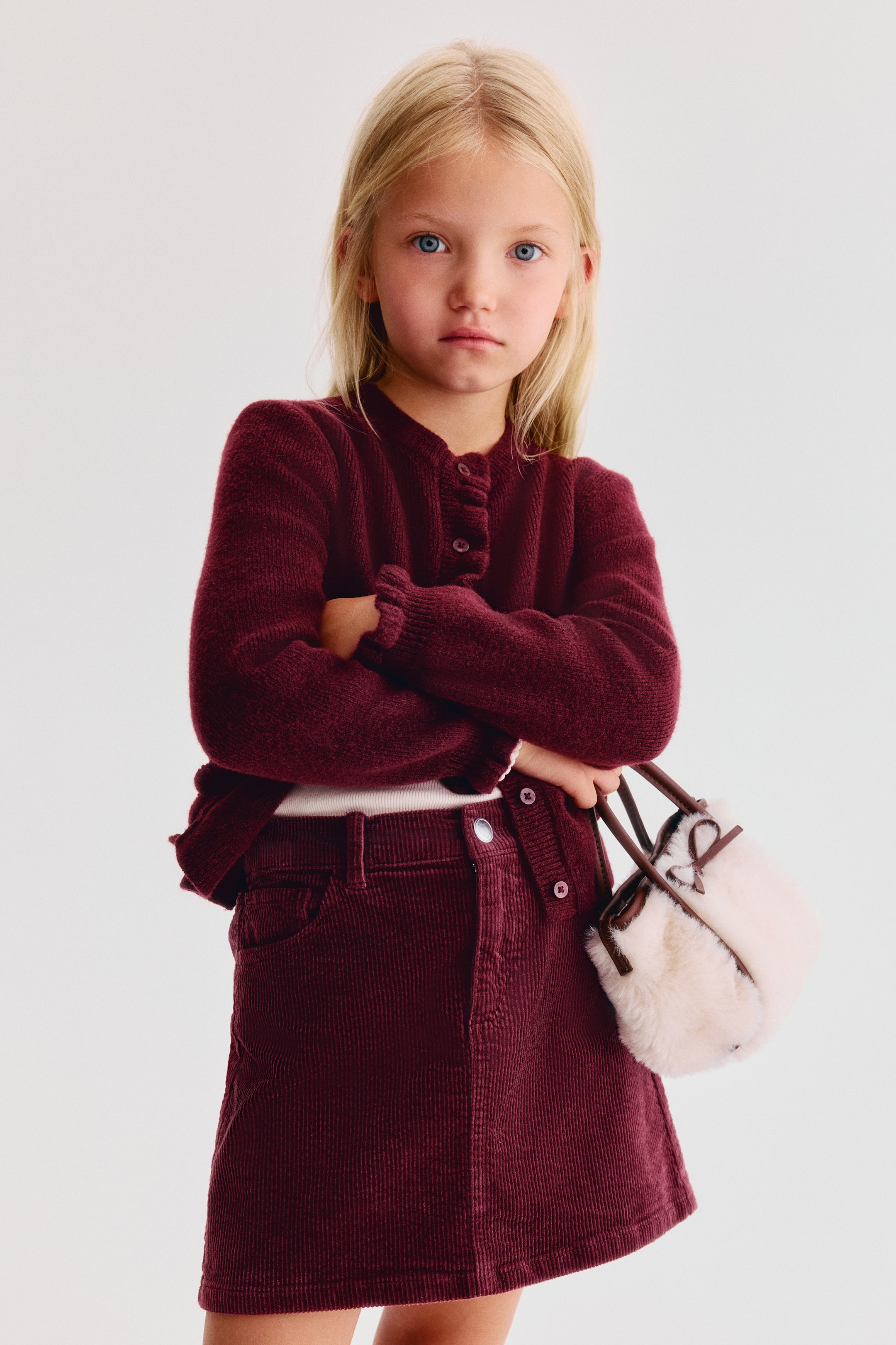 View larger image: A front-facing view showcases a burgundy corduroy A-line skirt featuring a structured waistband with belt loops, a silver snap closure, and five-pocket styling.