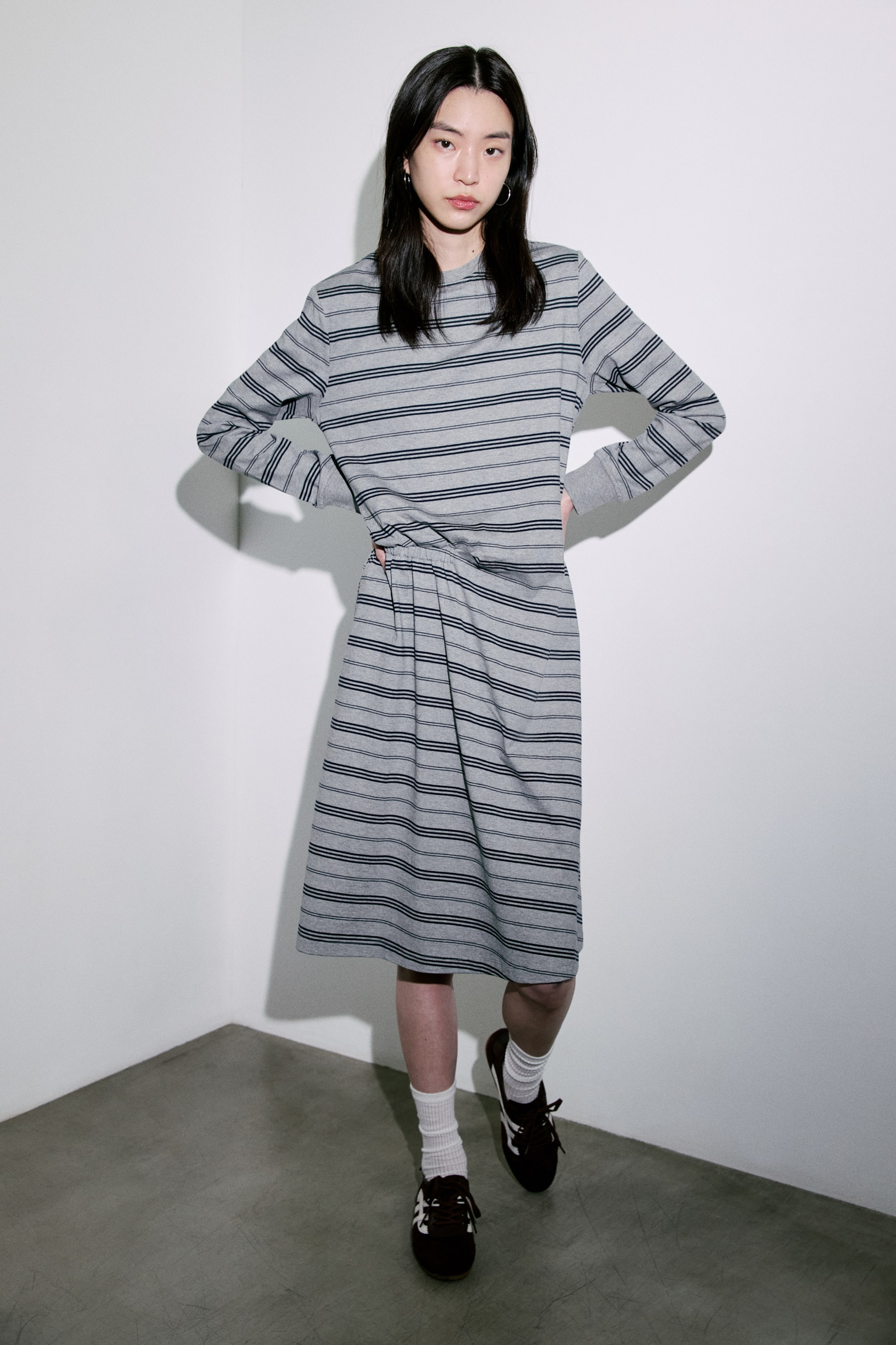 View larger image: A grey and black striped dress features a crew neck design, long sleeves with ribbed cuffs, and horizontal stripes of varying thickness. It gathers at the waist and flows into a midi-length skirt, perfect for a stylish yet comfortable look.