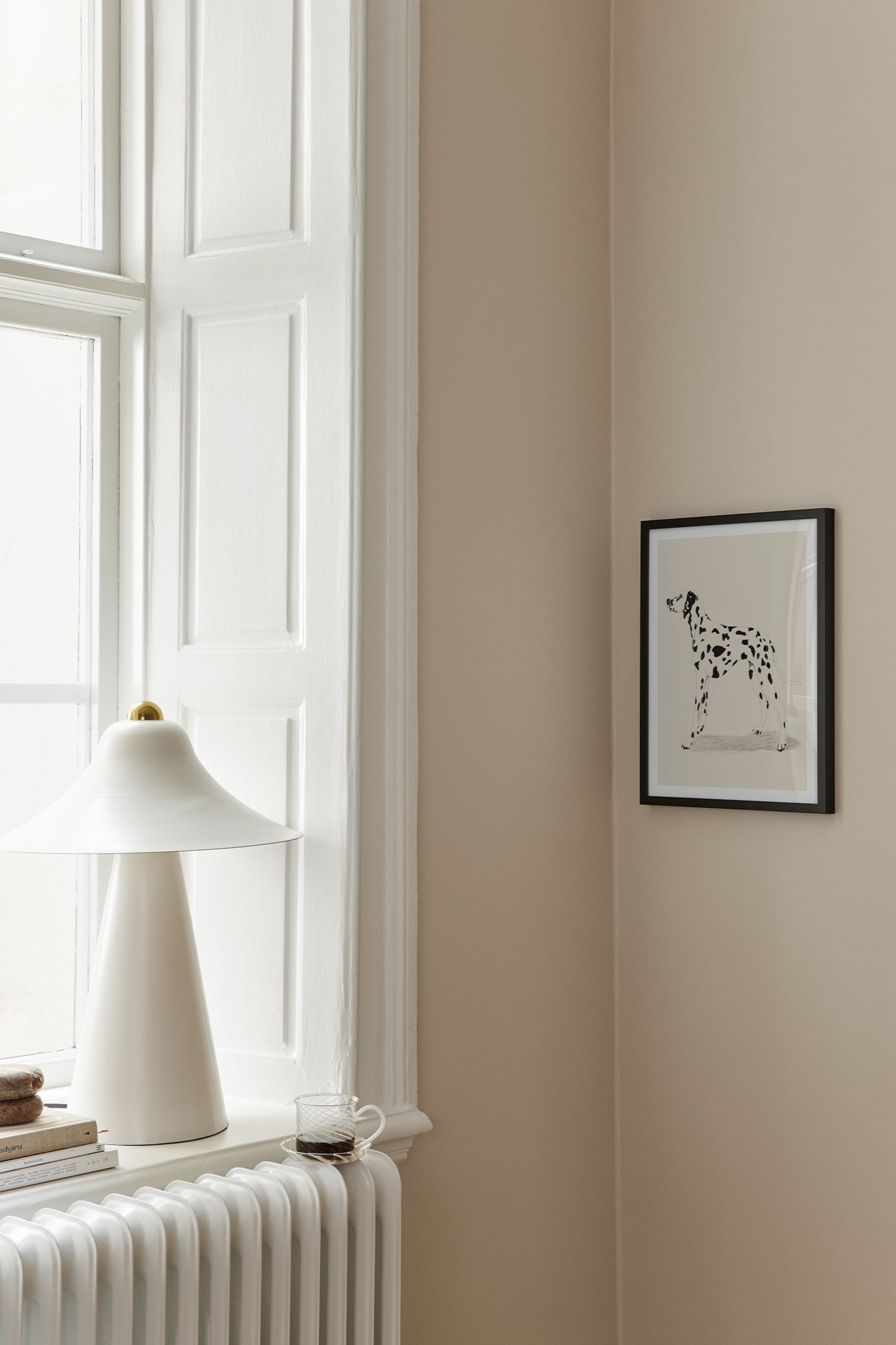 Größeres Bild ansehen: Ein gerahmter Kunstdruck mit einer schwarz-weißen Illustration eines stehenden Dalmatiners auf hellbeigem Hintergrund. Das Kunstwerk ist in einem schlanken schwarzen Rahmen eingefasst und hängt an einer Wand.