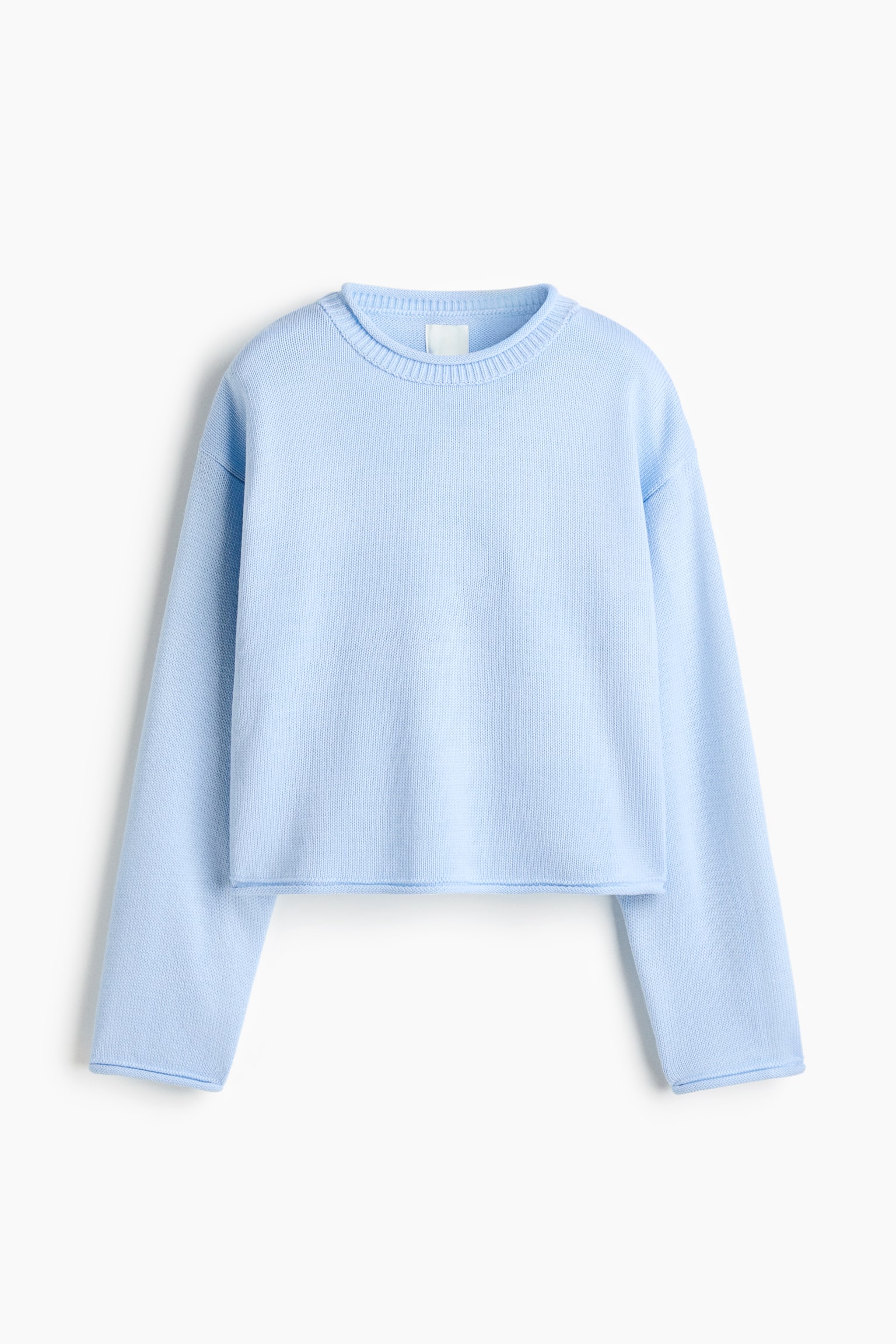 A light blue knit sweater is shown from the front, featuring a cropped, boxy fit with dropped shoulders and long, wide sleeves. The sweater displays a ribbed crew neck and clean-finished, slightly rolled edges at the cuffs and hem.