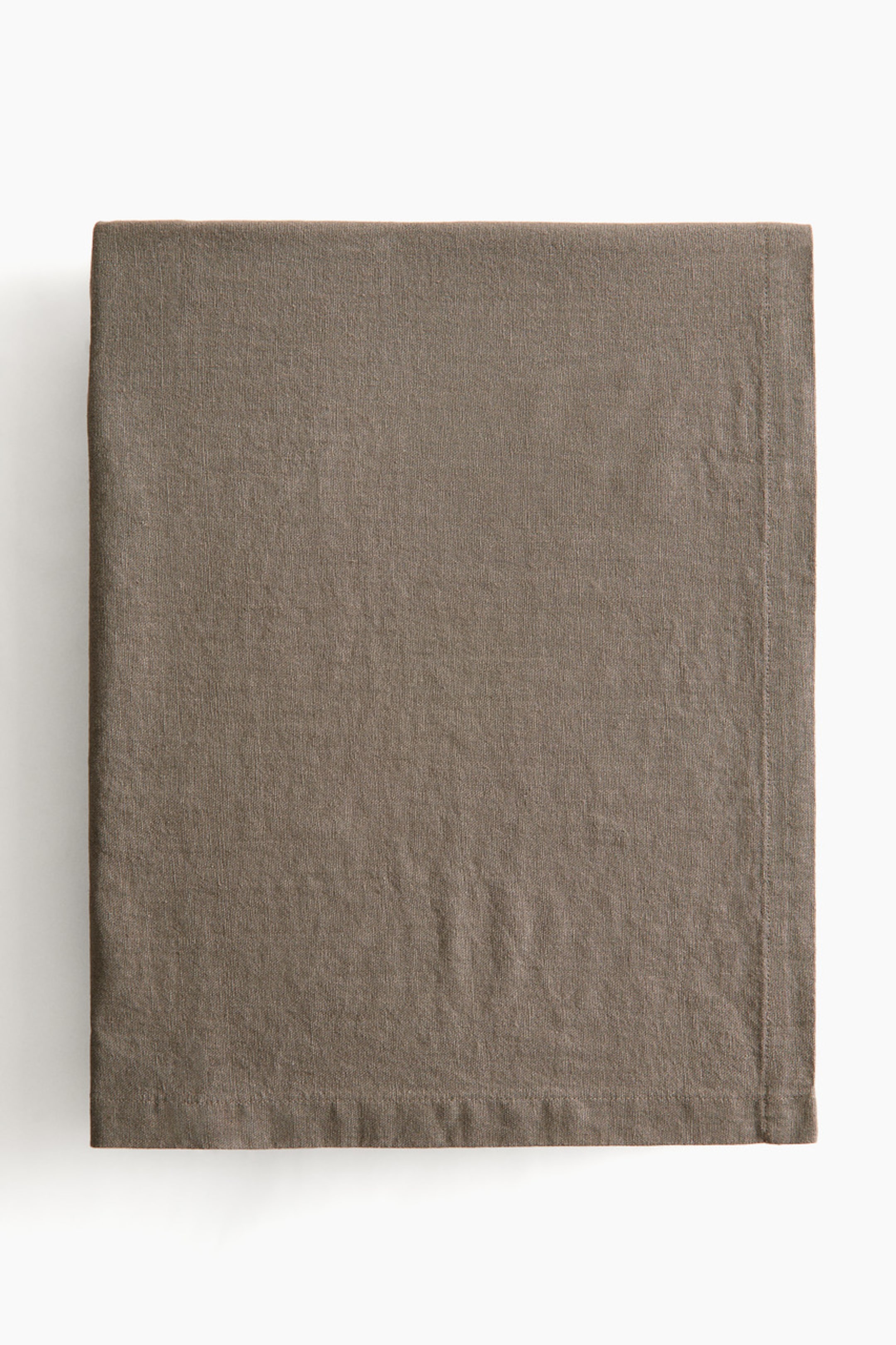 View larger image: The tablecloth, rectangular in shape, is displayed from the front, neatly folded. It features a visible weave texture in a neutral brown hue and is finished with a folded hem.