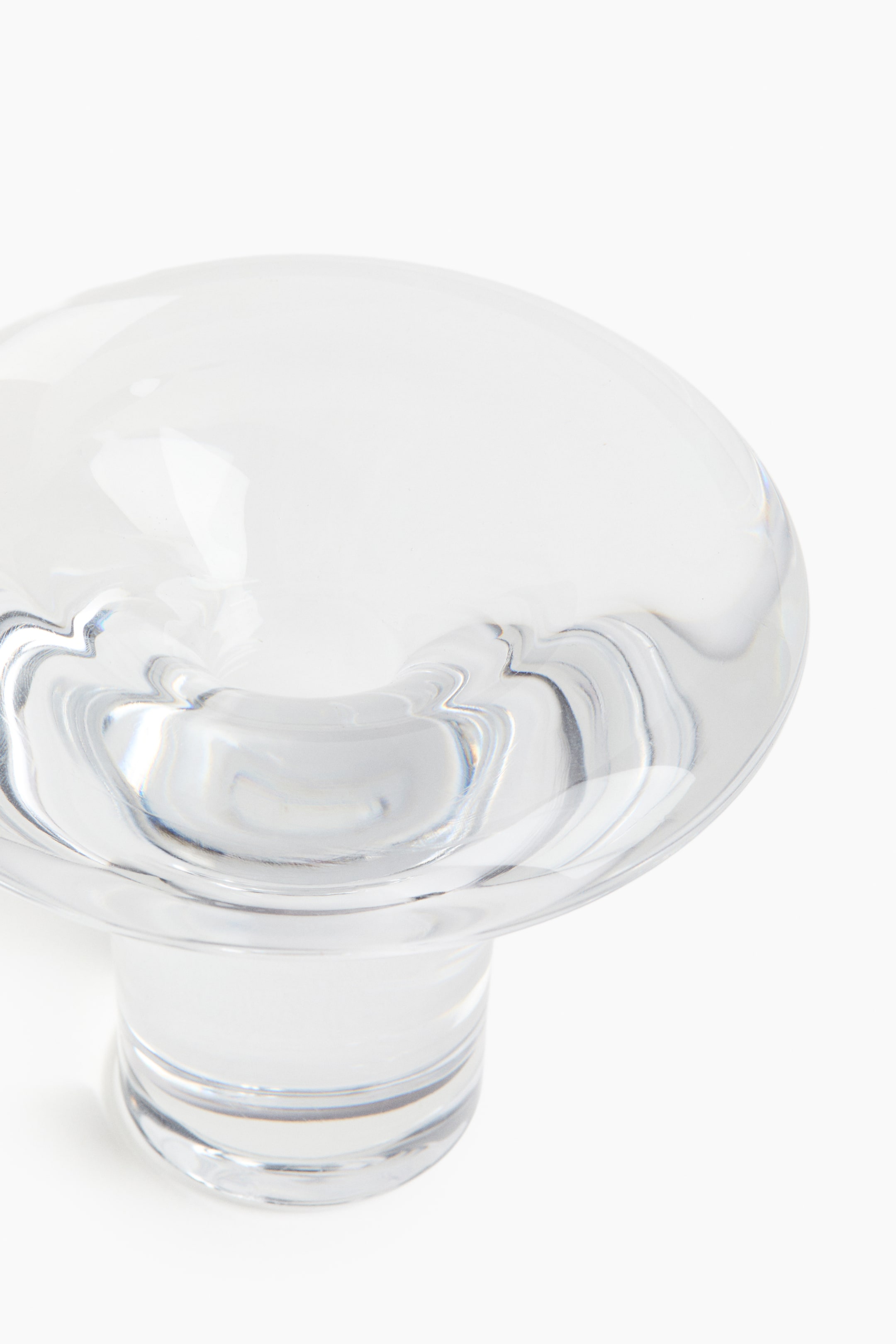 View larger image: A high clear glass candle holder is displaying a rounded, dome-like top that is transitioning to a wide, flared rim. Its smooth, transparent surface is catching and reflecting light, creating a sculptural appearance.