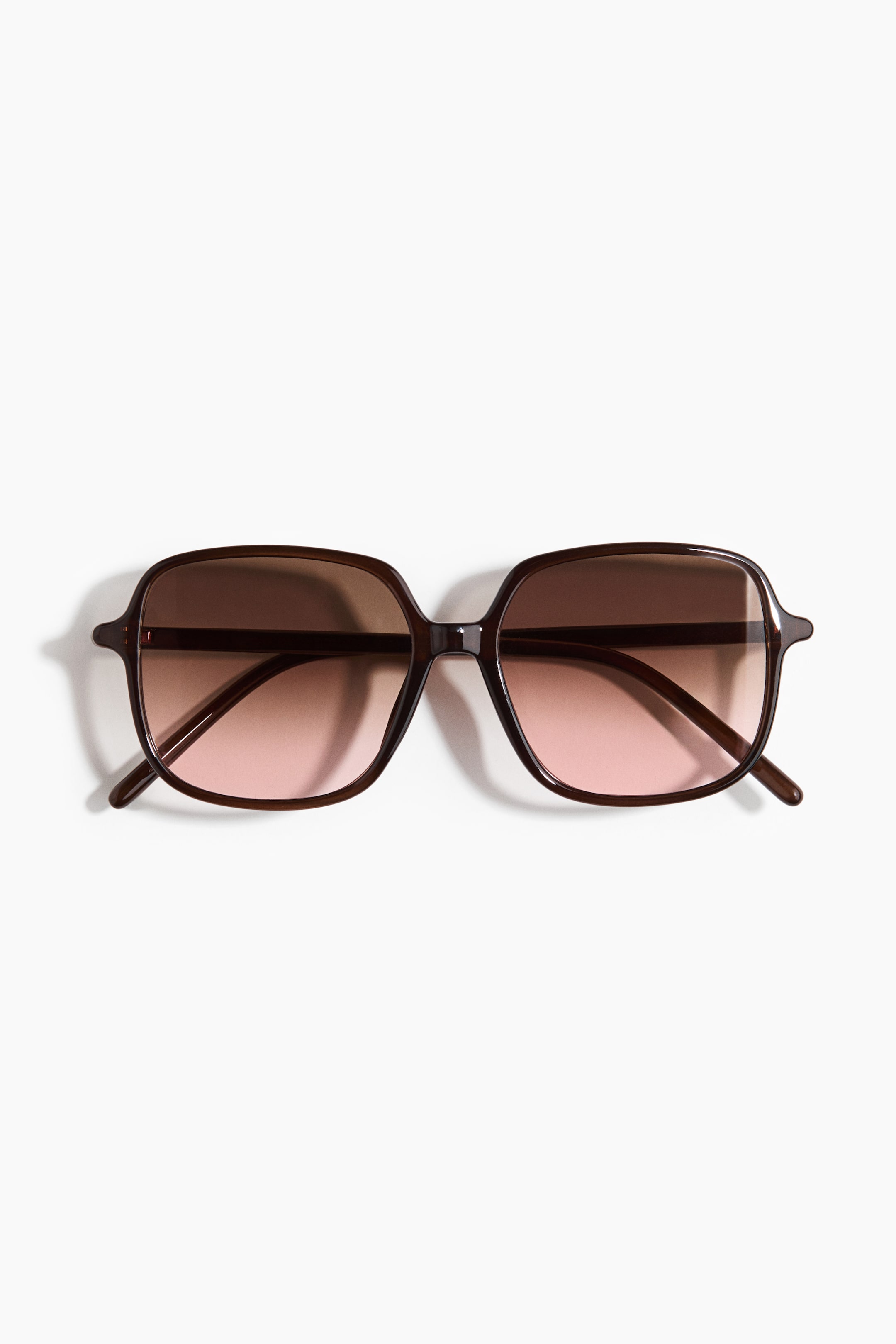 View larger image: A pair of sunglasses is facing FRONT, featuring dark brown, oversized, square frames. The lenses are displaying a gradient tint, transitioning from dark brown at the top to a light rosy brown at the bottom.