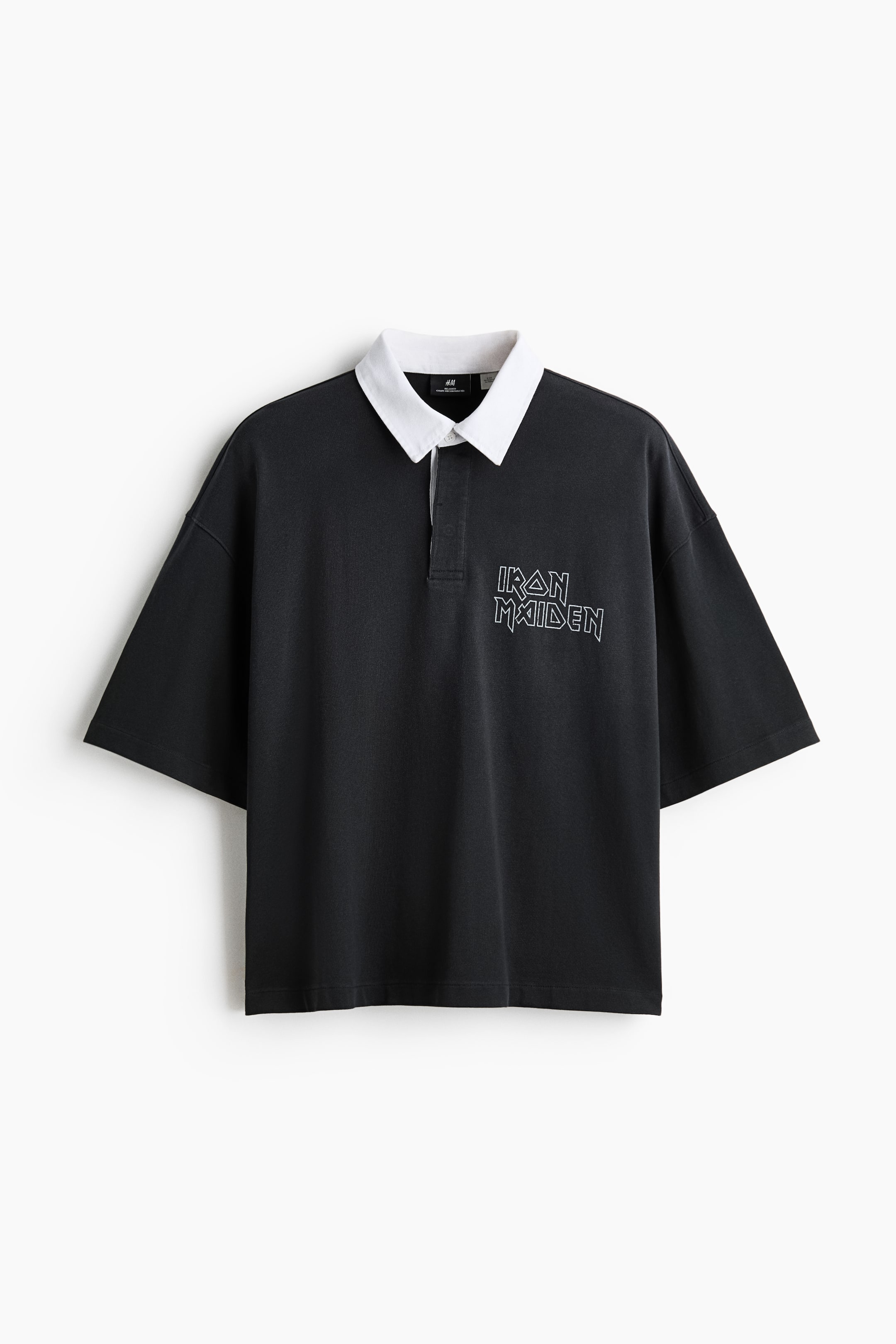 View larger image: A black polo shirt showcases a contrasting white collar and a two-button placket. It features an "Iron Maiden" text logo in white outline on the left chest, with short, wide sleeves and an oversized fit.