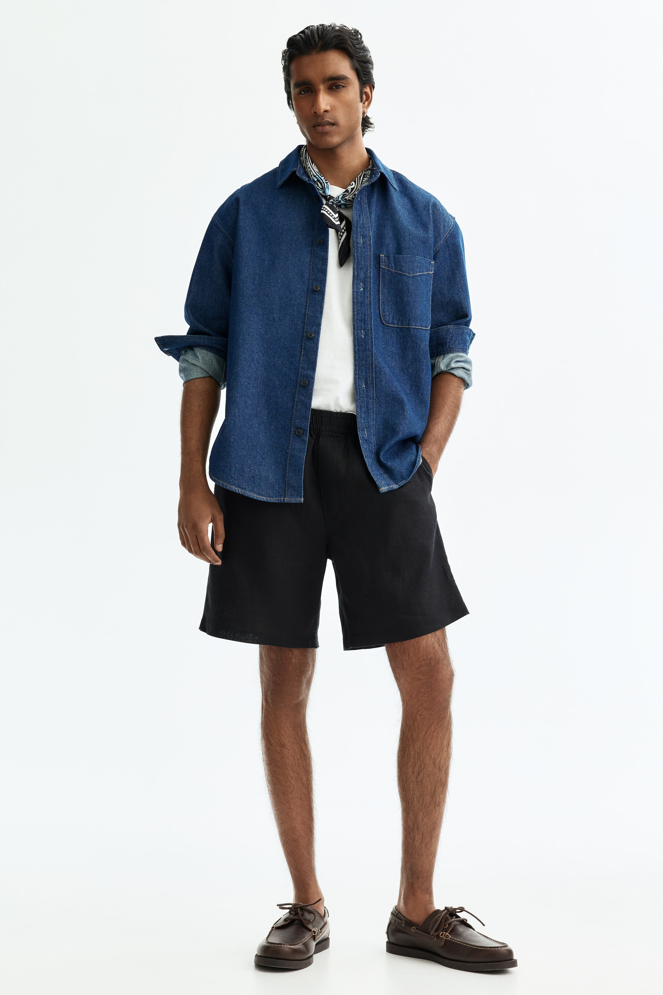View larger image: Black shorts showcase a relaxed fit with straight legs ending above the knee, an elastic waistband, and visible side pockets, presented from a front-facing angle.