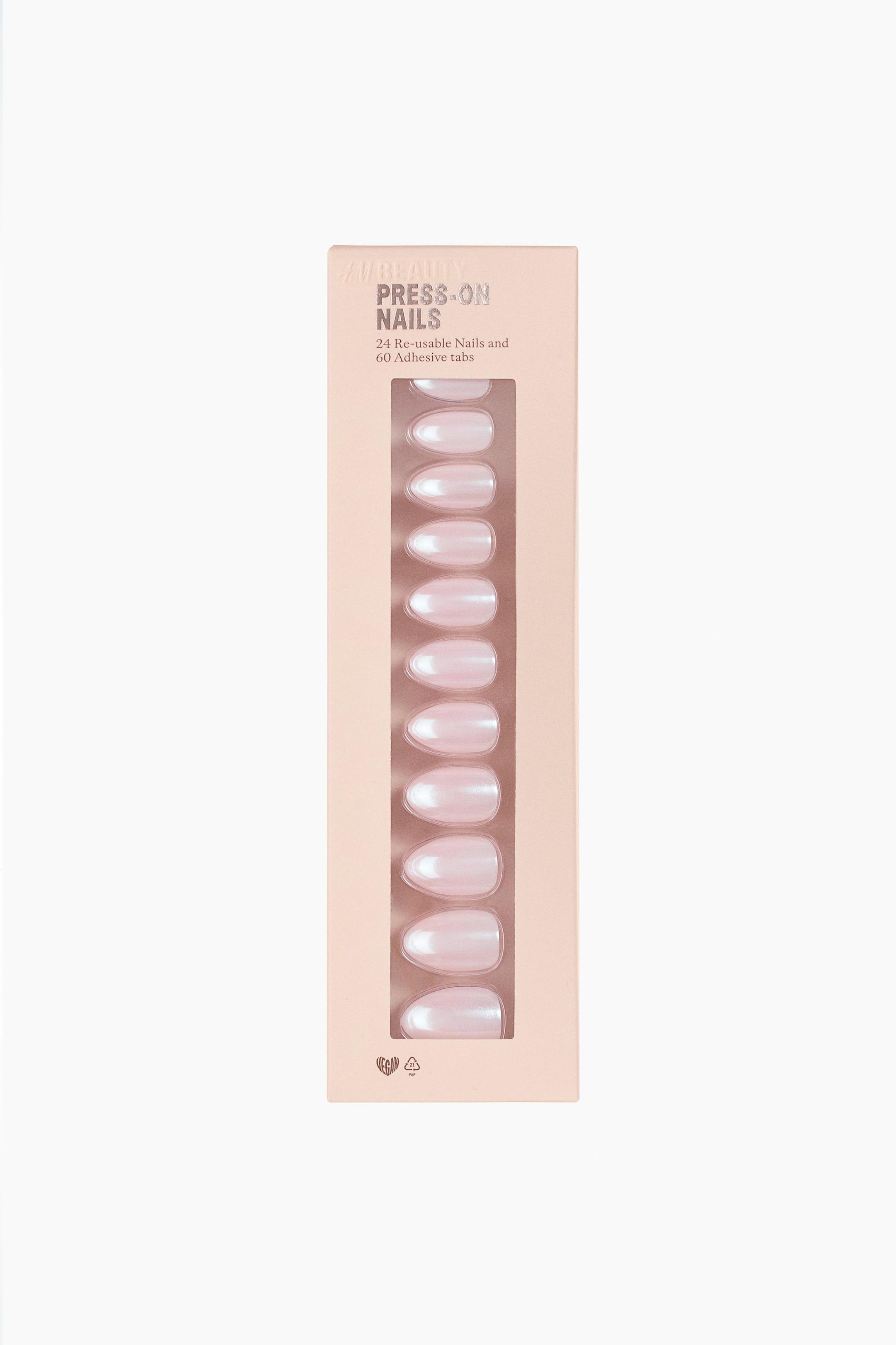 View larger image: A box of press-on nails featuring iridescent light pink, oval-shaped nails, displayed through a clear window. The light peach-coloured box presents ten individual nails arranged in two vertical columns, with text indicating "PRESS-ON NAILS" and "24 Re-usable Nails and 60 Adhesive tabs."