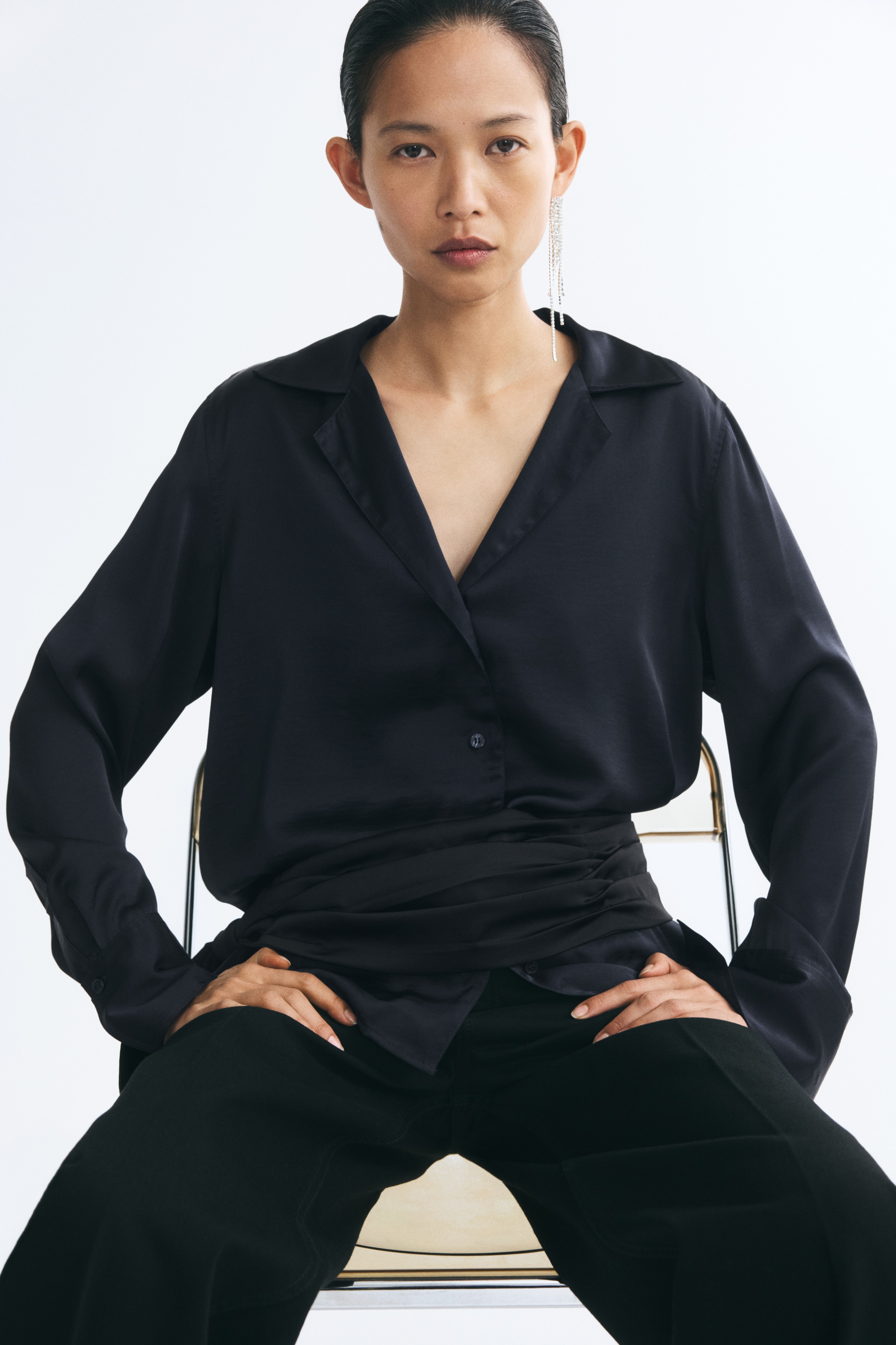 Má»t chiáº¿c Ã¡o blouse satin xanh navy Äáº­m ÄÆ°á»£c chá»¥p tá»« phÃ­a trÆ°á»c, ná»i báº­t vá»i cá» ve chá»¯ V thoáº£i mÃ¡i, hÃ ng cÃºc cÃ i phÃ­a trÆ°á»c vÃ  tay dÃ i káº¿t thÃºc báº±ng cá» tay Ã¡o rá»ng.