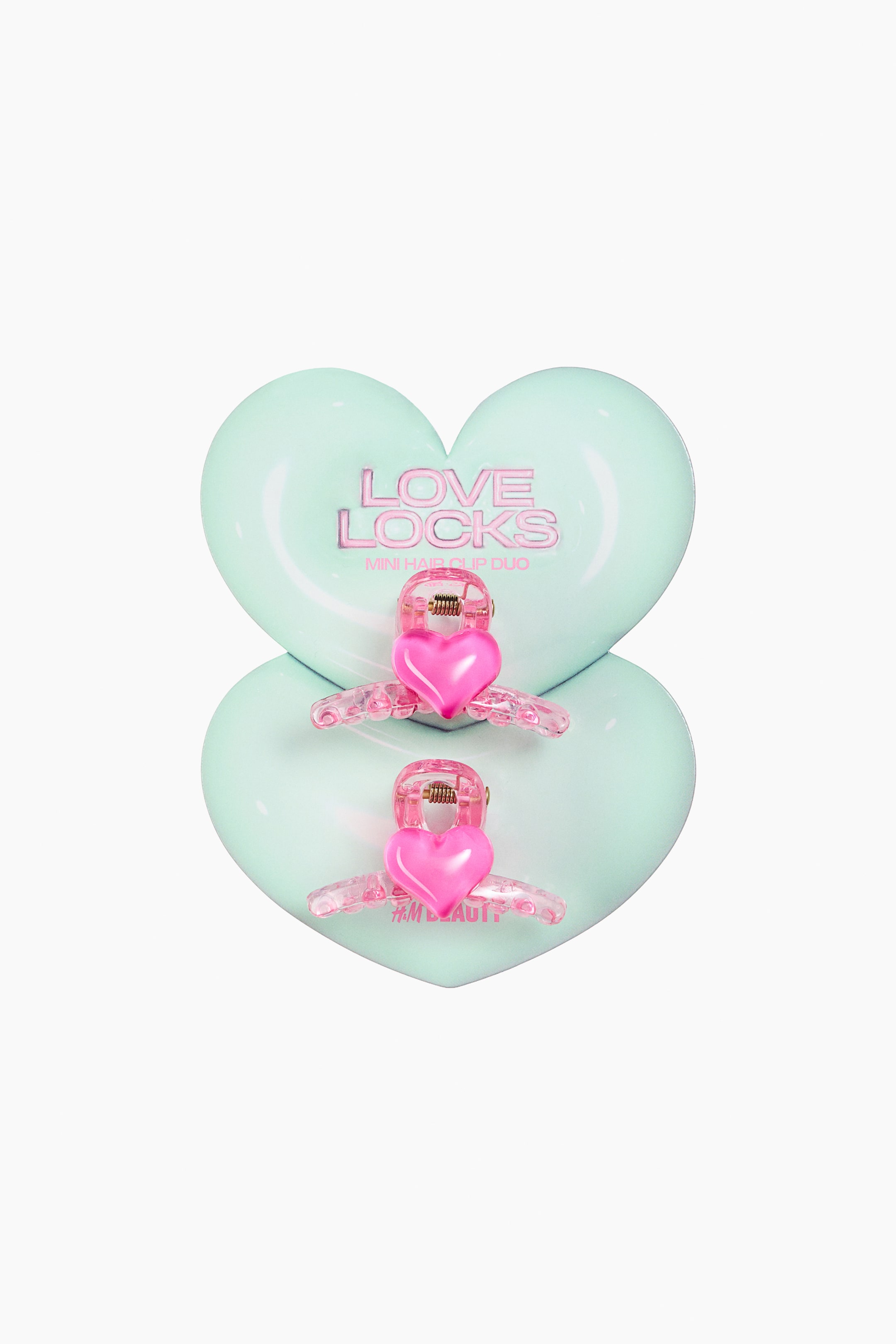 View larger image: A 2-pack of mini hair claws is featuring transparent pink plastic bodies. Each claw is showcasing a solid pink heart design on its top, facing FRONT, with a metal spring mechanism visible.