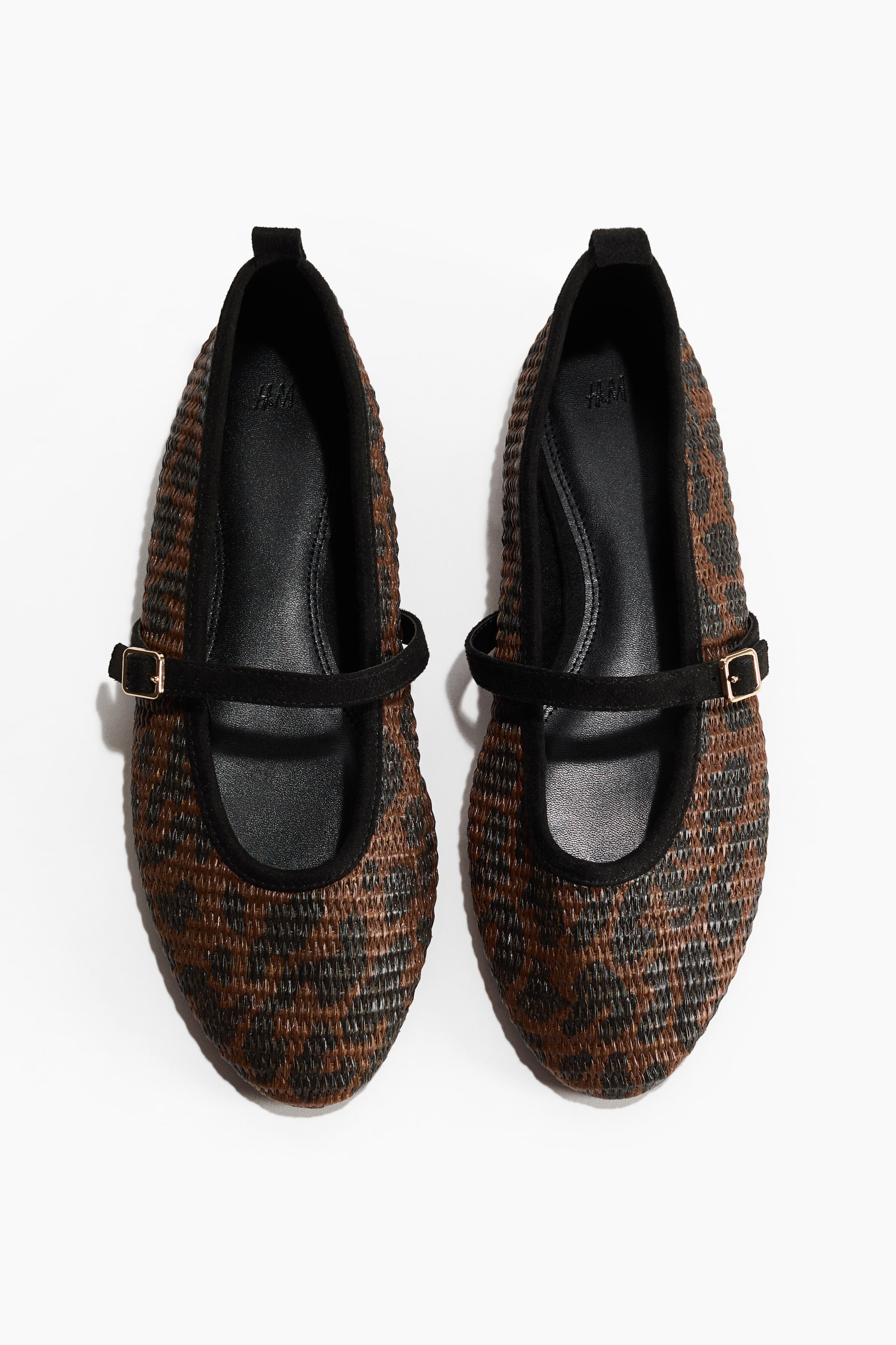 View larger image: A pair of Mary Jane ballet flats showcases a woven brown and black checkered pattern, viewed from the front. Each shoe features a black trim around the opening and a black strap across the instep, secured with a gold-colored buckle.