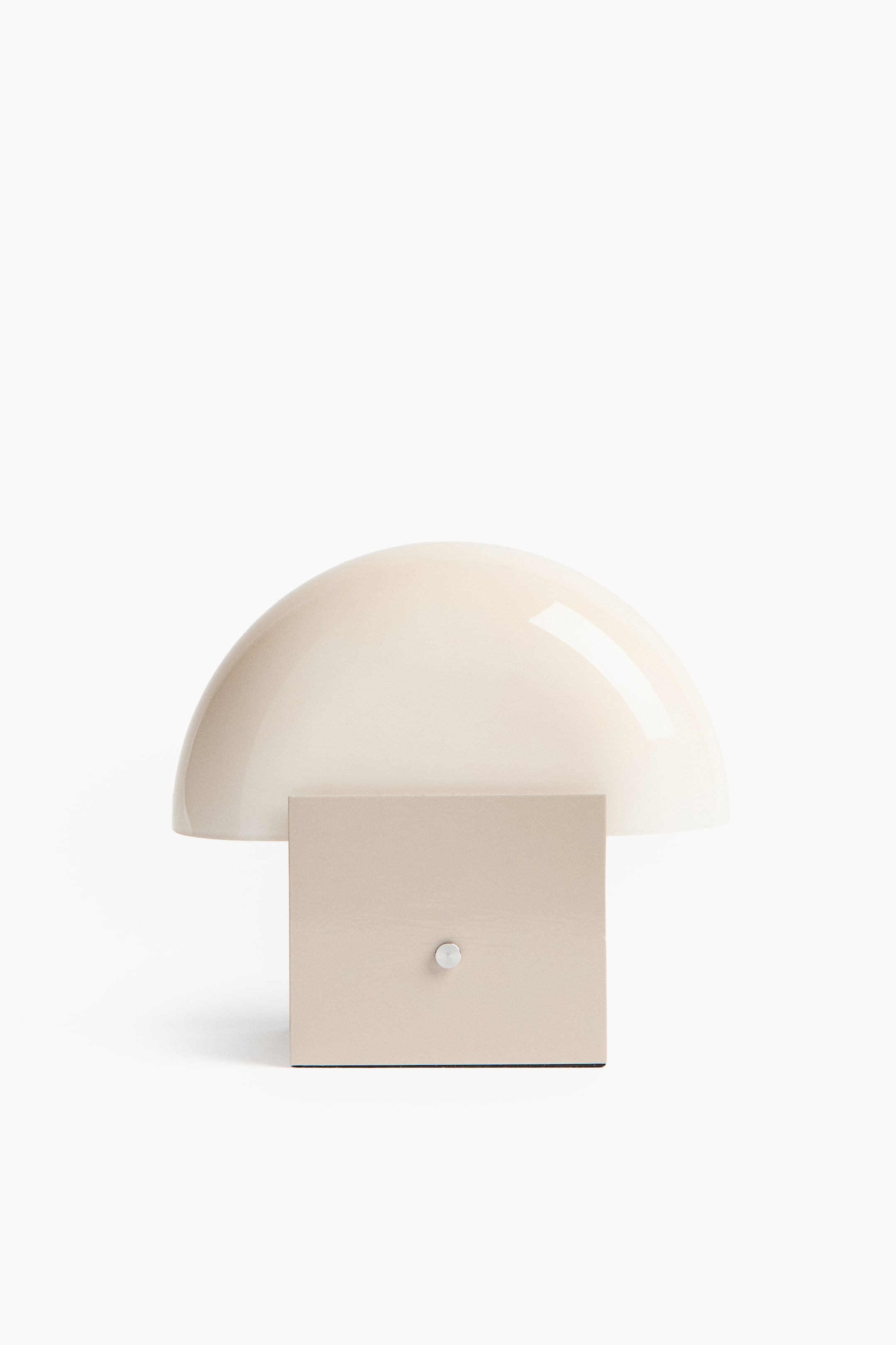 Größeres Bild ansehen: Eine Tischlampe mit einem glänzenden, cremeweißen, kuppelförmigen Schirm, der auf einem rechteckigen, hellbeigen Sockel ruht. Ein kleiner, silberfarbener Knopf ist mittig an der Vorderseite des Sockels angebracht.