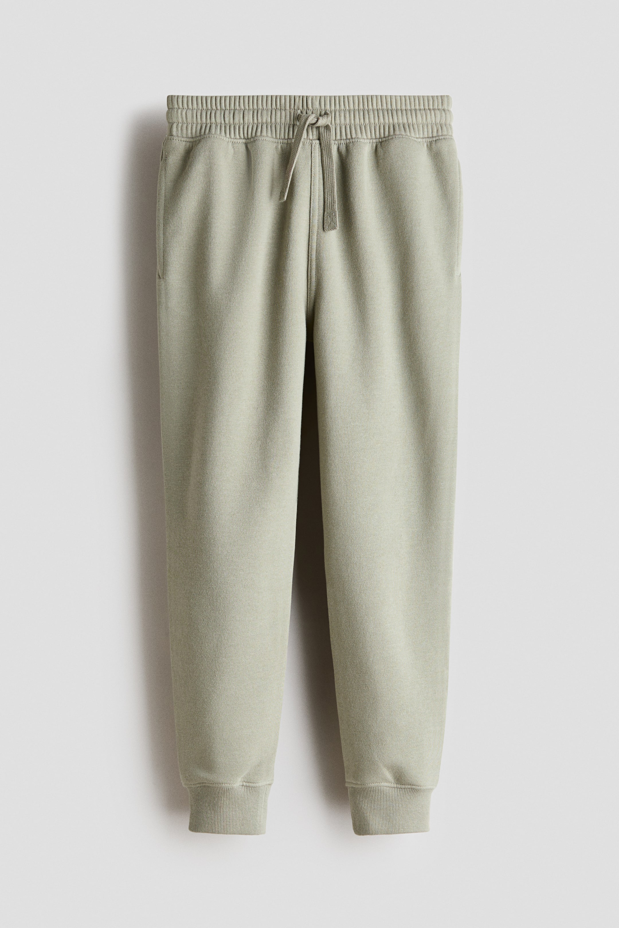 Agrandir l'image: Joggers vert clair présentés de face, confectionnés dans un tissu sweat léger, avec une taille élastiquée à cordon de serrage, des poches latérales discrètes et des ourlets côtelés.