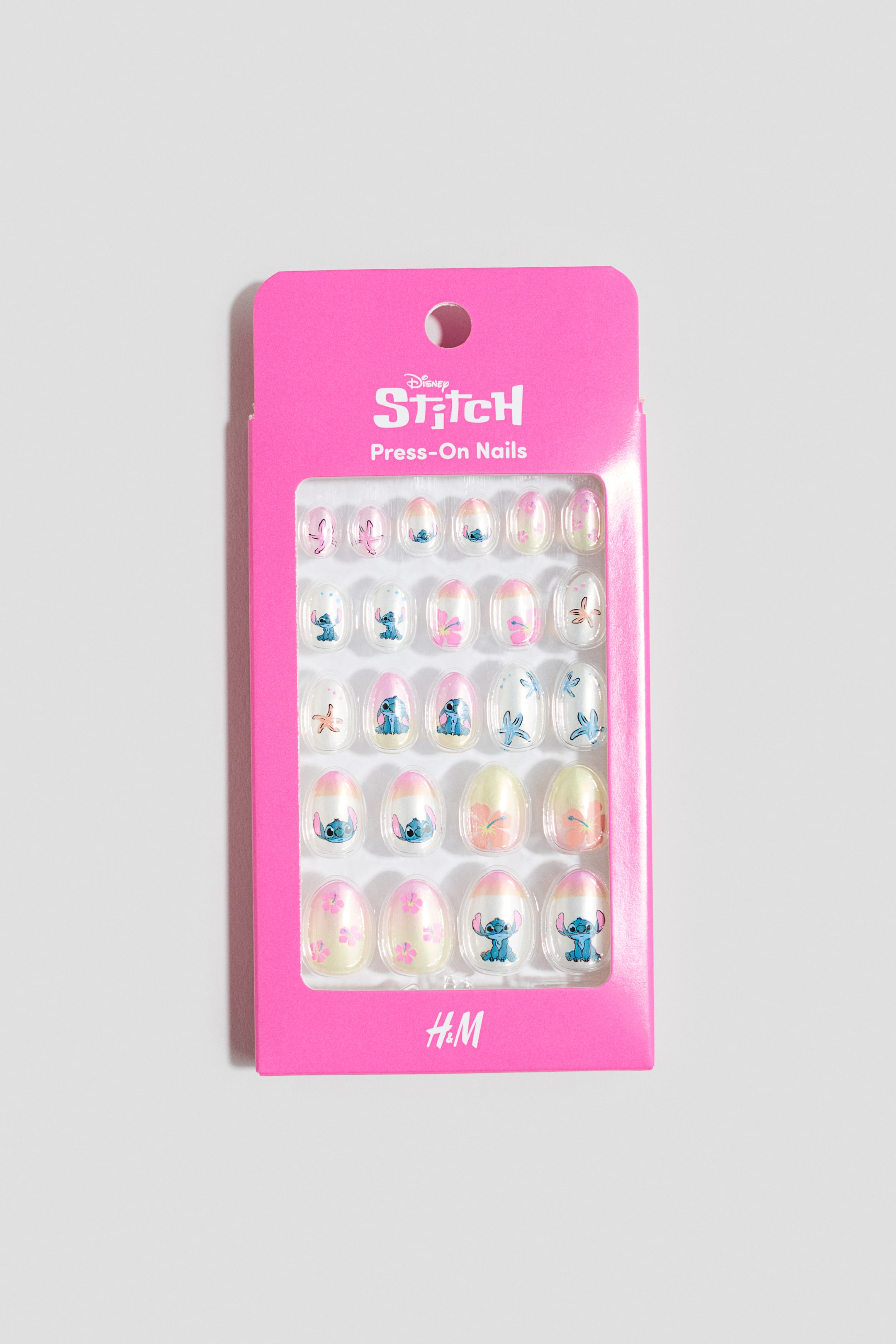 Agrandir l'image: Un ensemble de vingt-quatre ongles pressés de forme ovale, orientés vers l'avant, est emballé dans un emballage en carton rose vif, doté d'une fenêtre transparente. Les ongles présentent divers motifs, y compris le personnage Stitch, des papillons et des motifs floraux en bleu, rose, blanc et jaune, sur des bases transparentes, rose pastel et jaune clair, certains affichant également des pointes blanches ou roses.
