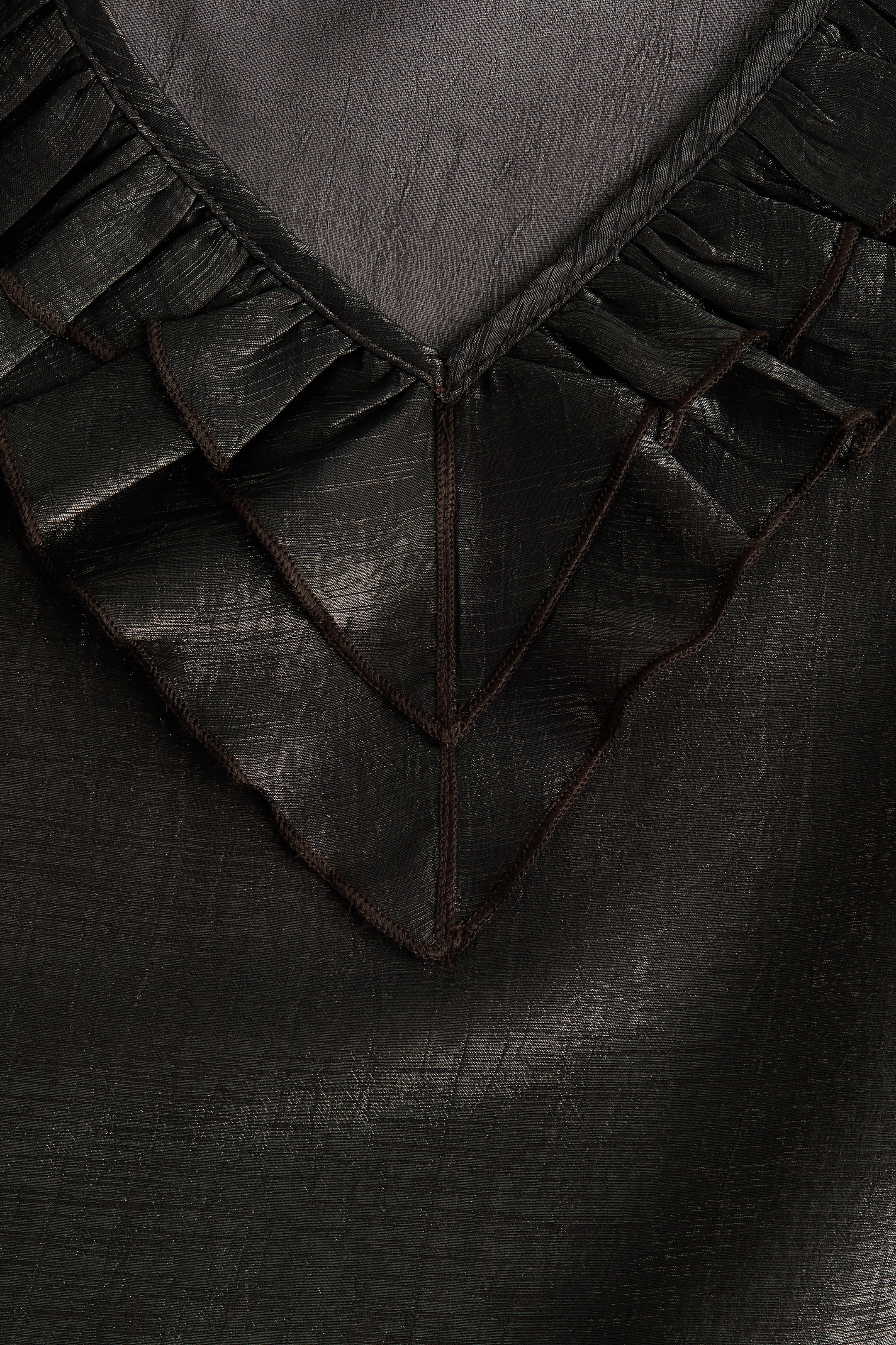 Ver imagem maior: Uma peça escura e texturizada apresenta um decote em V com folhos franzidos. Abaixo dos folhos, painéis geométricos com costura castanha-escura visível criam um padrão em forma de chevron na parte da frente.