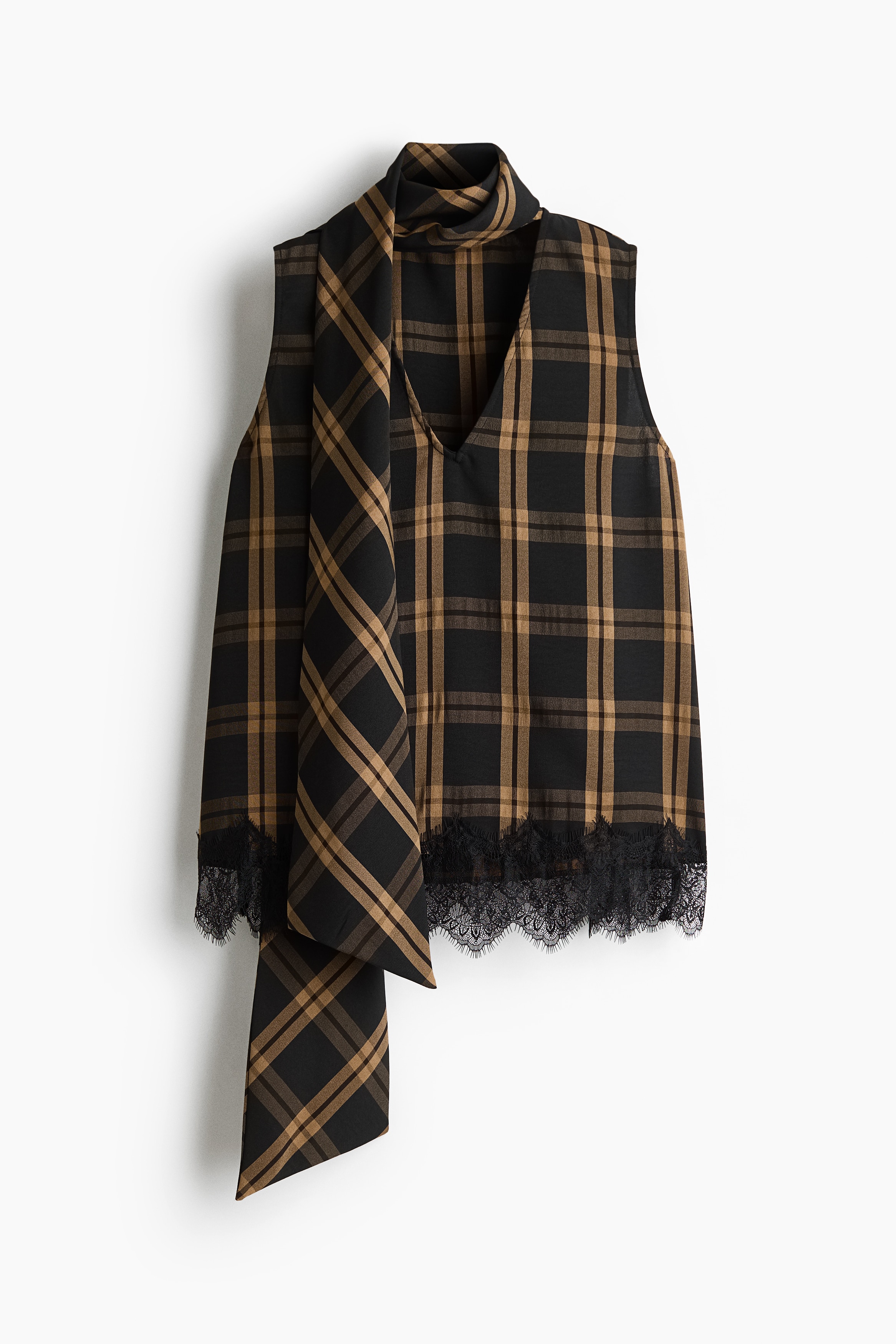 A sleeveless plaid top in brown and black woven fabric is worn by the model, featuring a V-shaped front opening, black lace-trimmed hem, and a long, wide scarf collar wrapped around the neck. The top is styled with a matching plaid skirt.
