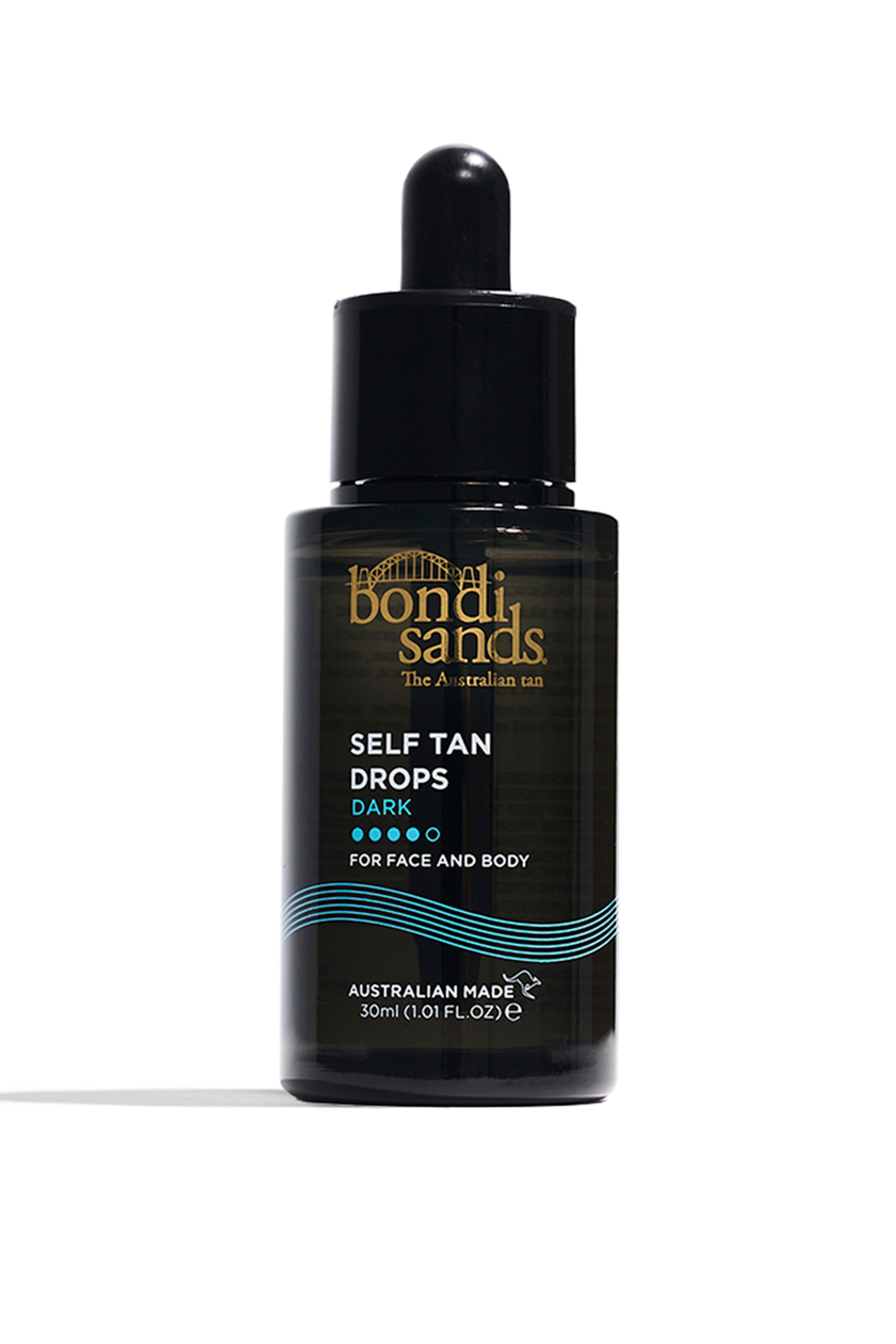 Se større billede: En mørk glasflaske med Bondi Sands Self Tan Drops står oprejst og vender fremad. Den har en sort pipettehætte og en etiket, der viser 'Bondi Sands' i guld, 'SELF TAN DROPS DARK' i hvid tekst og blå bølgede linjer nær bunden.