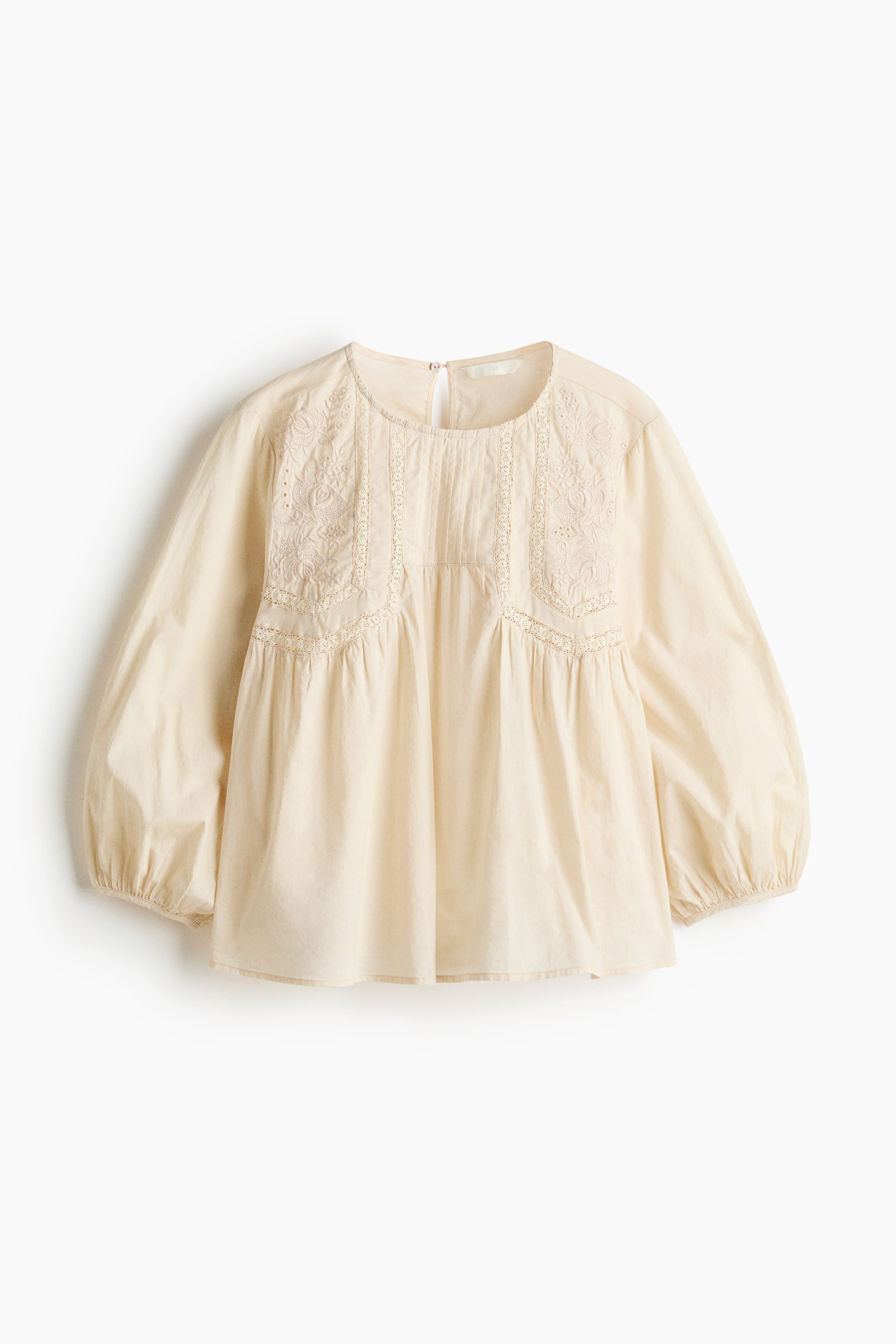 View larger image: A loose-fit blouse in a light cream hue is depicted from the front. It showcases a round neckline, a gathered yoke embellished with broderie anglaise, lace insets, and pintucks across the chest, along with 3/4-length balloon sleeves featuring narrow elastication at the cuffs.
