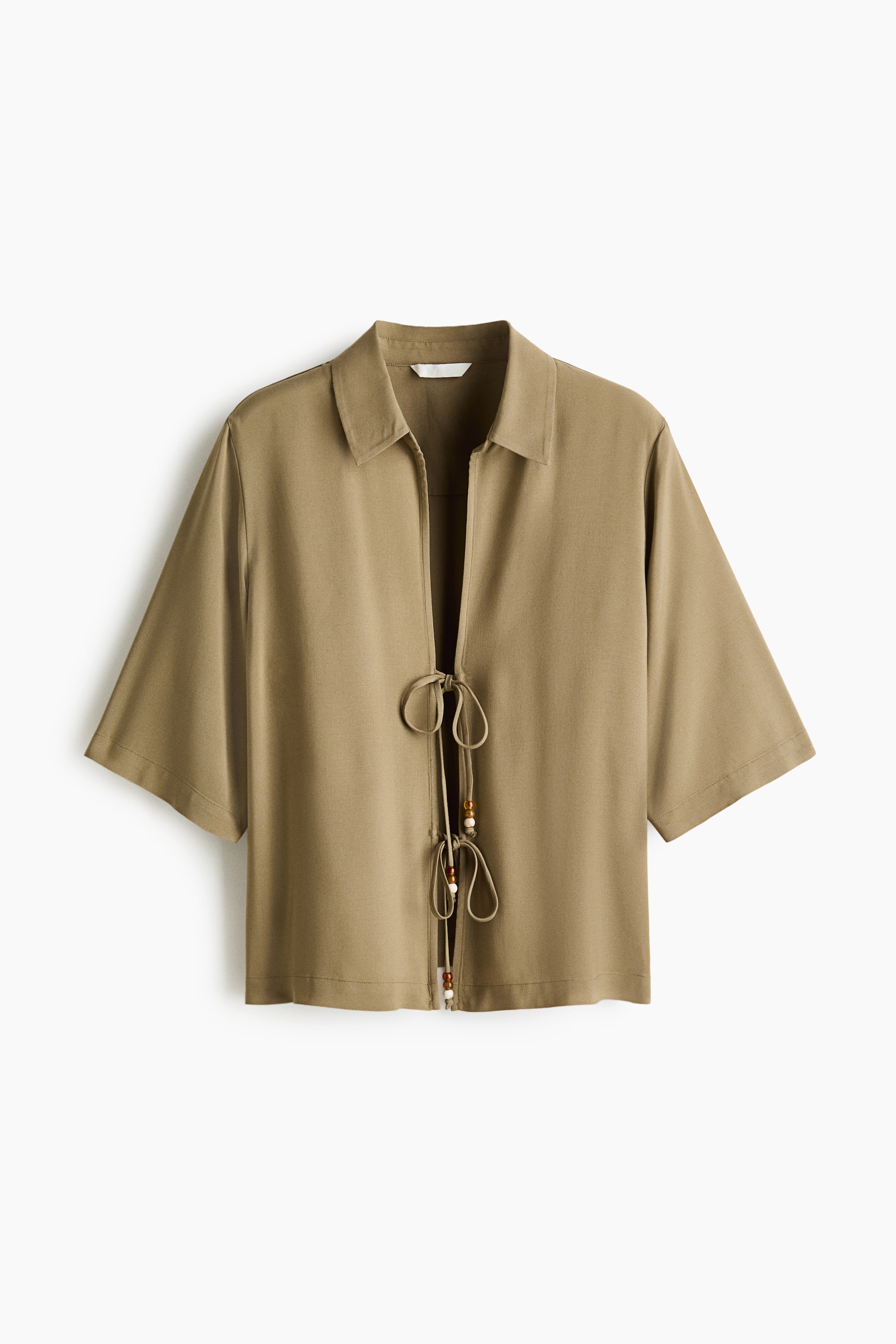 View larger image: A front view of an olive-green open-front top is shown, featuring a pointed collar and short, wide sleeves. Its central tie closure is adorned with decorative light and dark wooden beads.