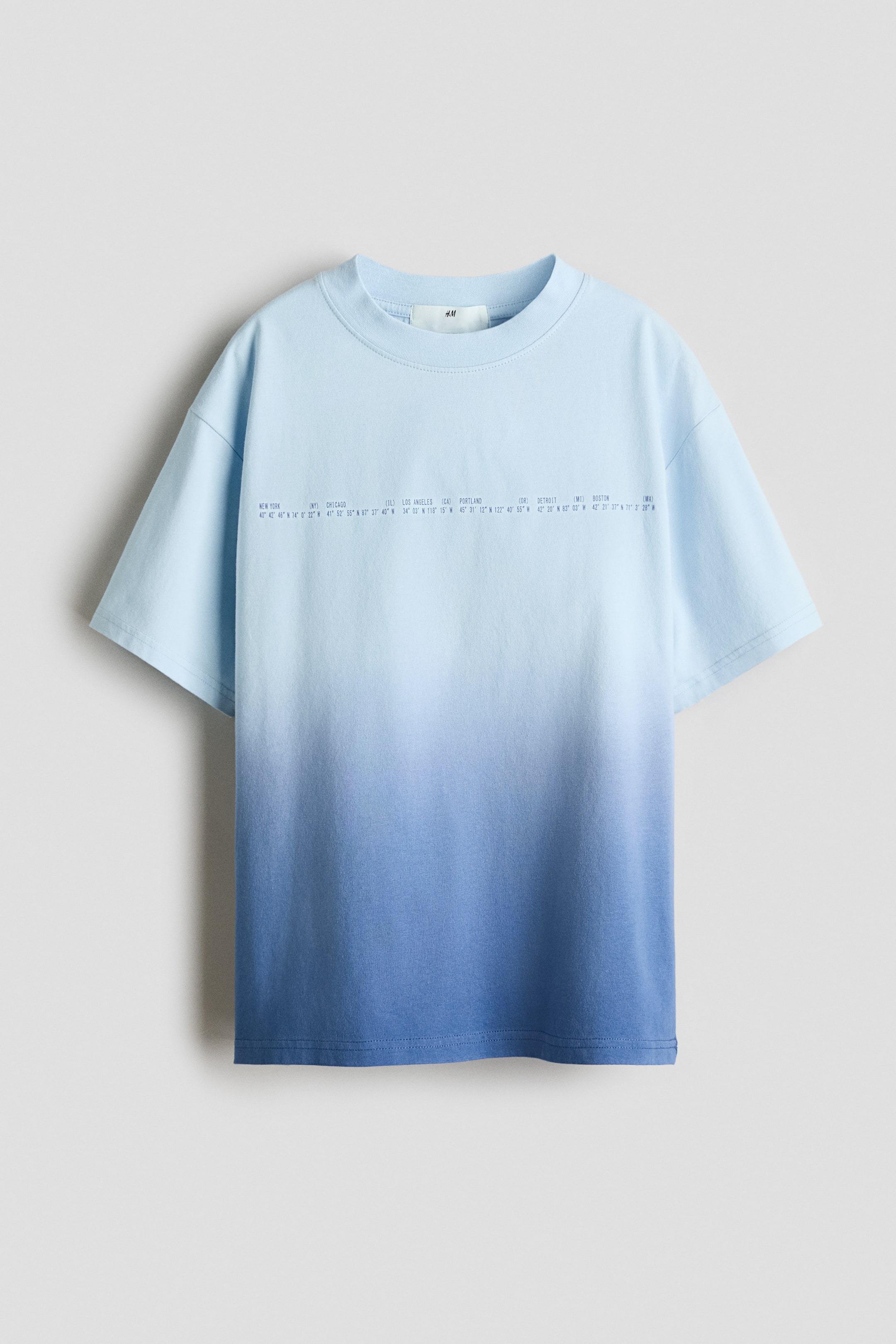 Grotere afbeelding bekijken: Een losvallend T-shirt van zachte katoenen jersey met een ombré ontwerp dat overgaat van lichtblauw bovenaan naar donkerder blauw onderaan. De voorkant is voorzien van een horizontaal bedrukt tekstmotief, een ronde halslijn met ribboord en subtiel verlaagde schouders.