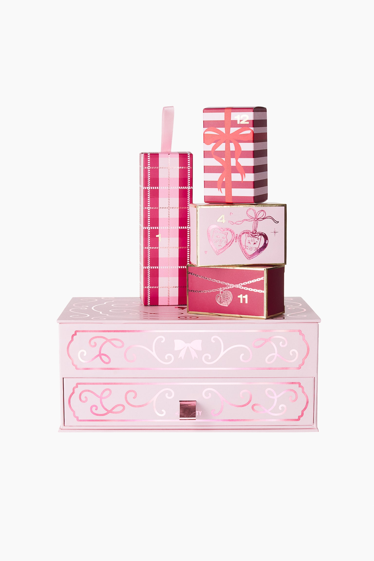 Le calendrier de lâAvent beauté de 12 jours présente un coffret décoratif rose clair, orienté de face, orné de volutes roses métalliques et dâun tiroir inférieur. Quatre petits coffrets cadeaux numérotés, aux différents motifs et illustrations roses, sont posés empilés sur le coffret principal.