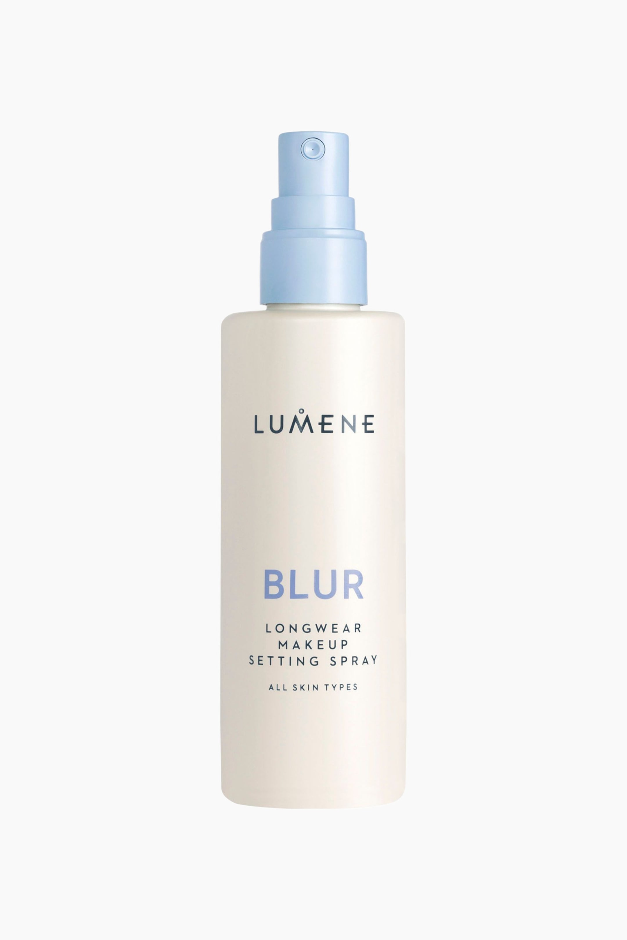 Se større billede: En flaske Lumene Blur Longwear Setting Spray står oprejst i en frontvendt visning og fremhæver en mat, råhvid cylindrisk flaske med en lyseblå spraypumpe-dyse. Forsiden af flasken viser mærkenavnet "LUMENE" i mørkegrå, ordet "BLUR" med store lyseblå bogstaver samt teksten "LONGWEAR MAKEUP SETTING SPRAY" nedenunder.