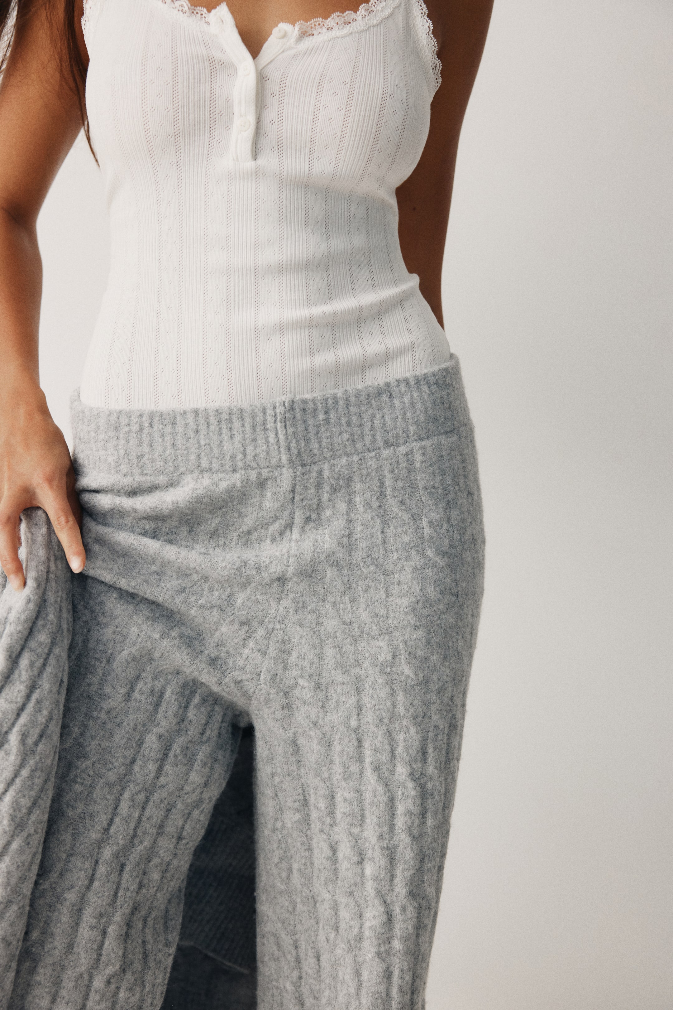 Agrandir l'image: Des pantalons en maille torsadée gris clair sont présentés, dotés d'une taille élastique et de jambes droites. Le tissu en maille douce présente un motif torsadé vertical visible.