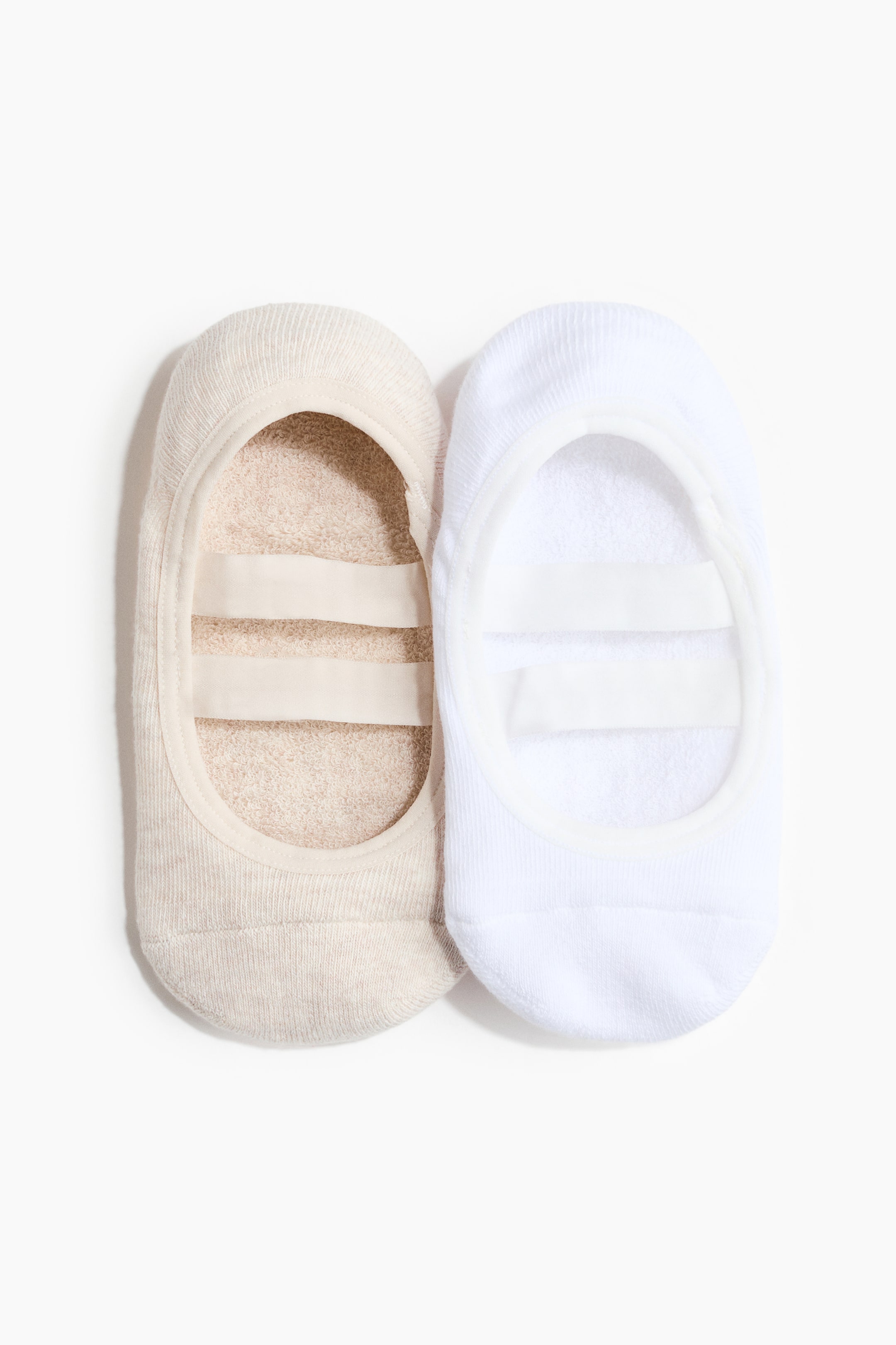 Ver imagen más grande: Un par de calcetines bajos para Pilates muestra un tejido suave, uno en beige y otro en blanco. Cada calcetín presenta dos correas elásticas que se extienden a lo largo de su empeine.