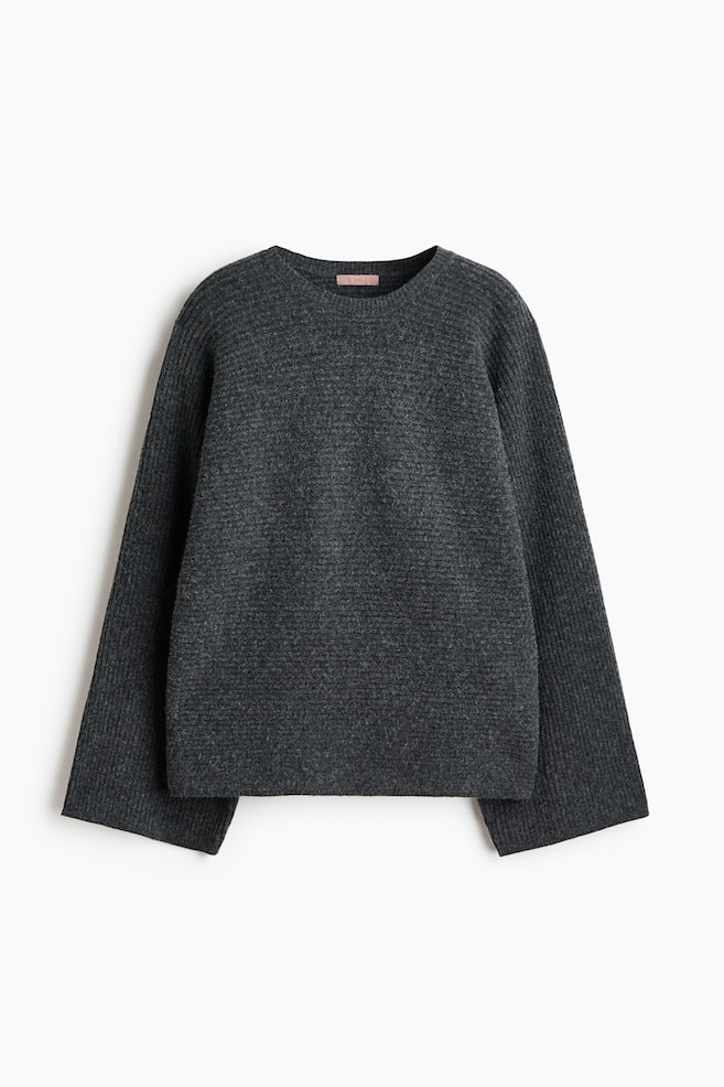 A charcoal grey knit sweater is shown from the front, featuring a ribbed crew neck, horizontal rib-knit construction on the body, and wide sleeves with vertical ribbing. - 1