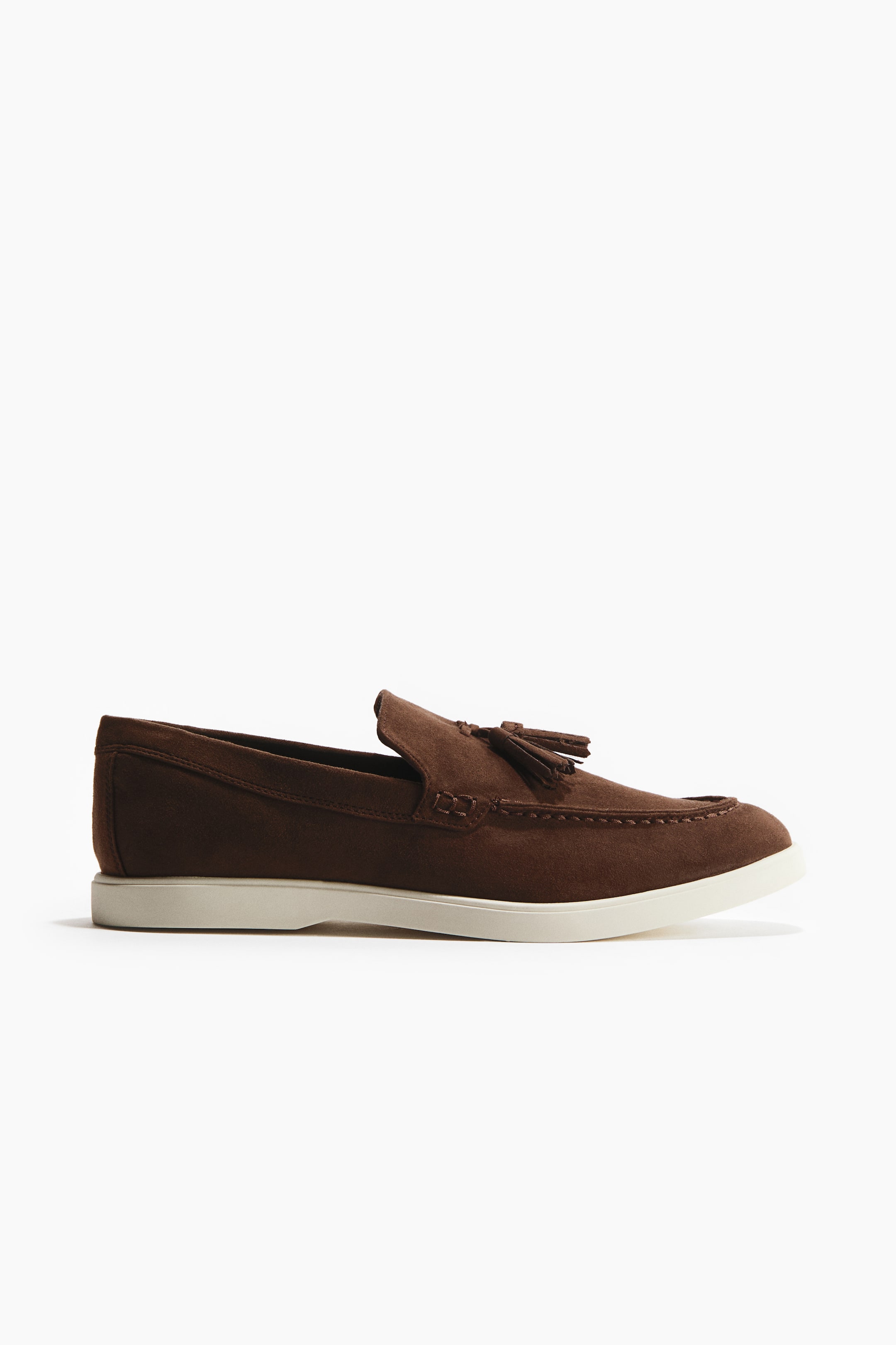 View larger image: Brown loafers are exhibiting a soft, napped finish with tassels and a moccasin seam at the front, displayed in a side profile on a white rubber sole.