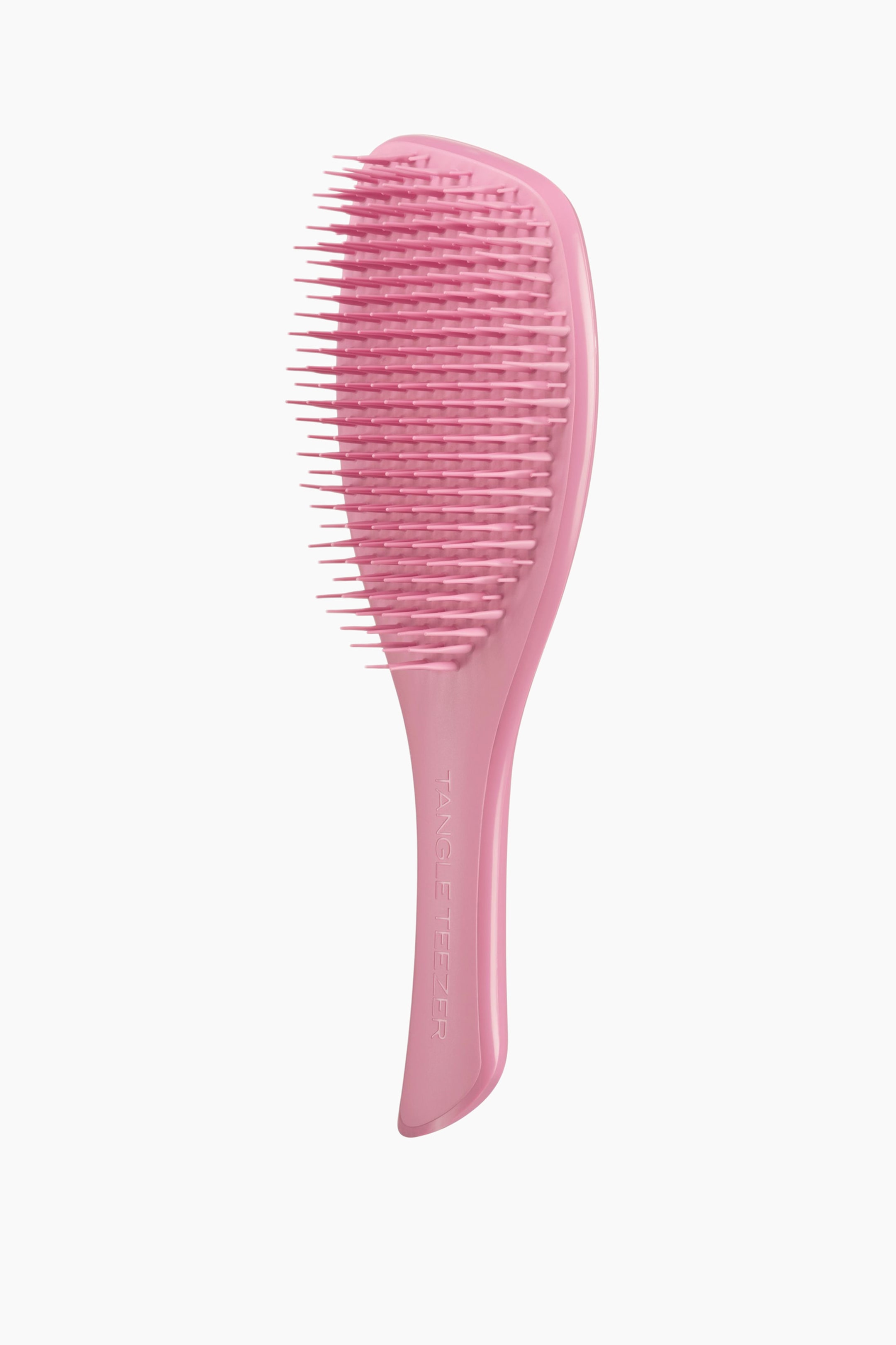Vis større bilde: En lys rosa hårbørste er vinklet litt mot høyre og har et padleformet hode med mange rosa, fleksible børstehår og et buet håndtak preget med «Tangle Teezer».