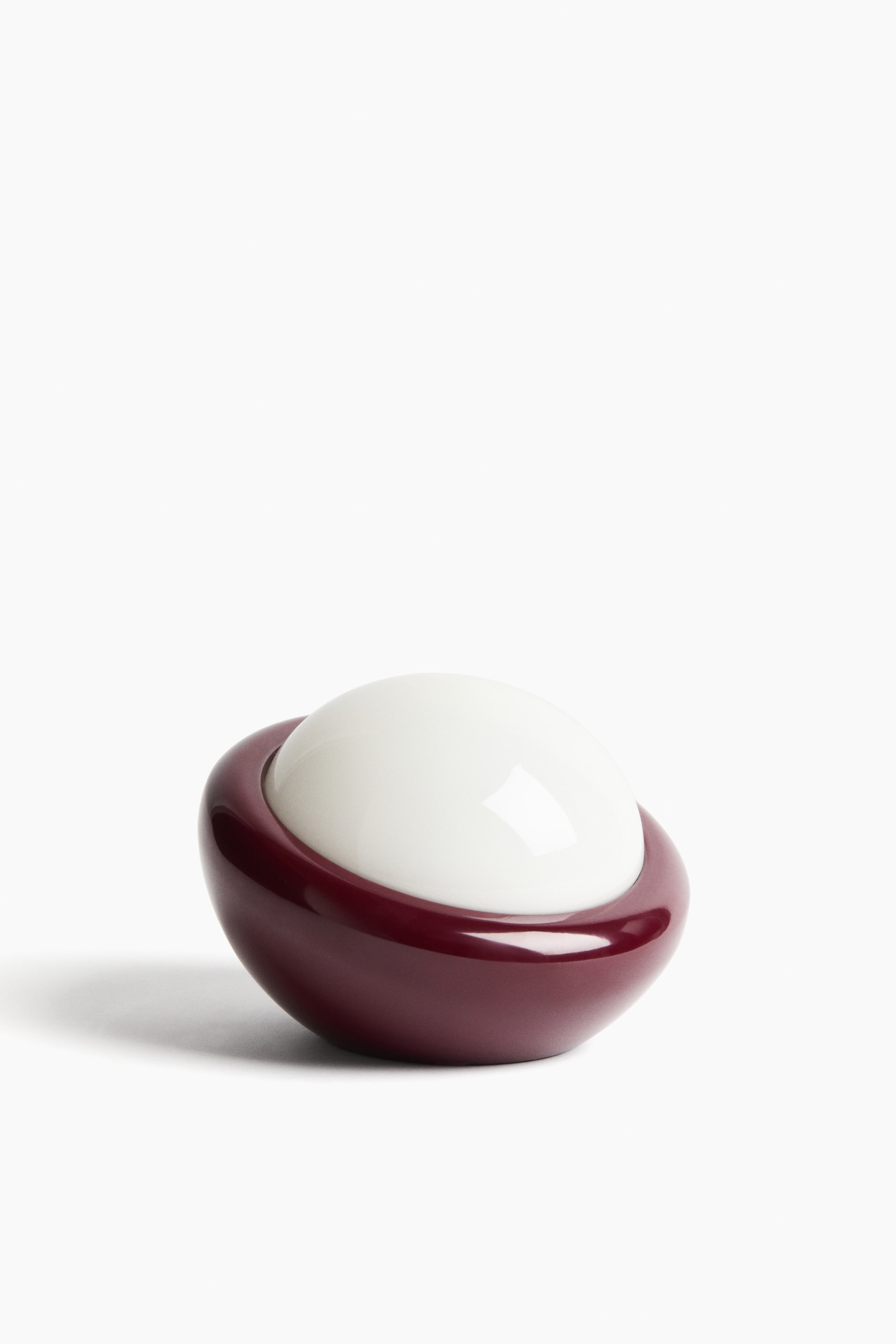 View larger image: This decorative piece consists of two parts: a glossy, dark maroon, oval base, and a smooth, off-white, dome-shaped lid that nestles within the base. Both surfaces elegantly reflect light.
