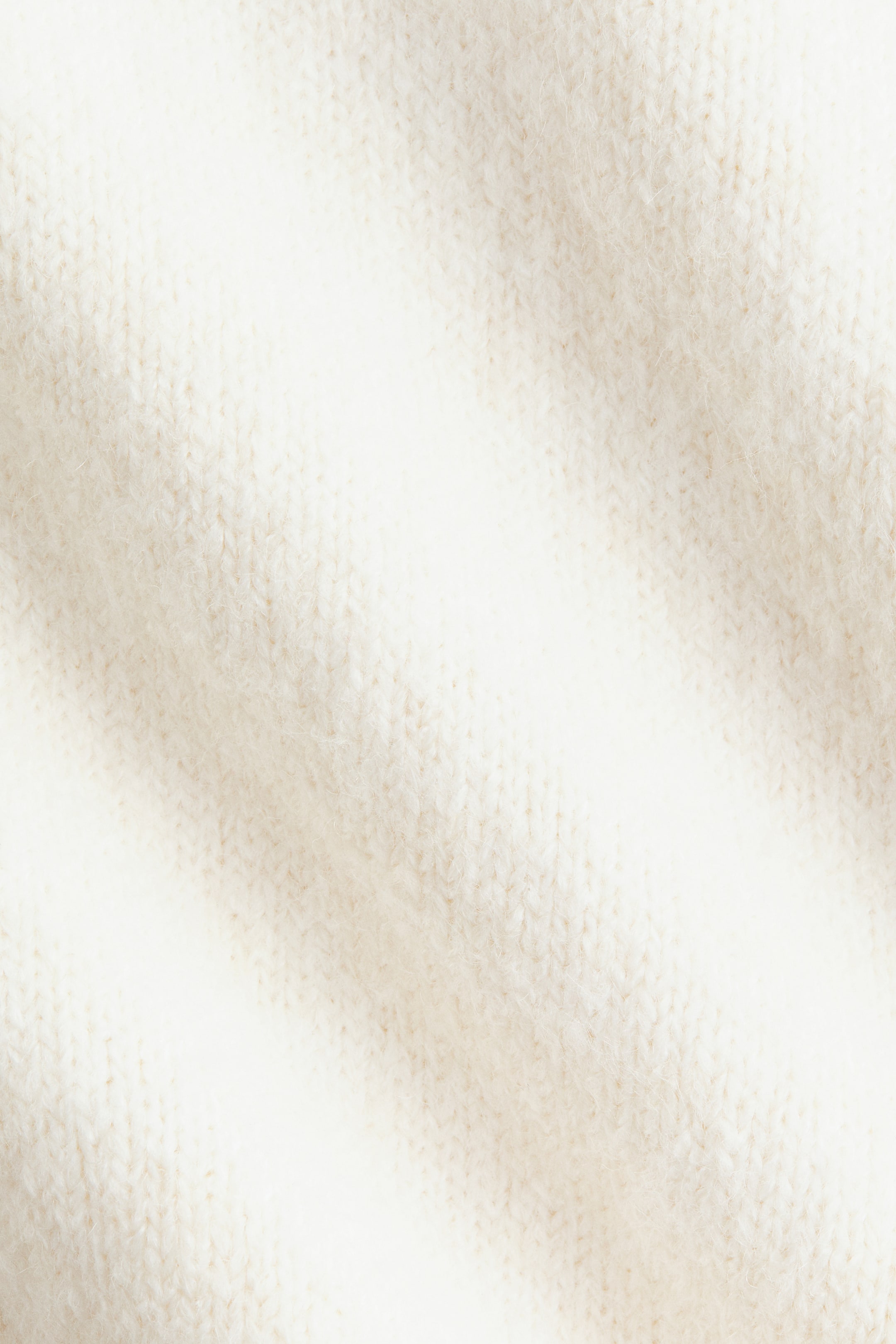 View larger image: Off-white knitted fabric is presenting a close-up view, showcasing its visible textured weave. The soft, slightly fuzzy surface is displaying subtle diagonal folds.