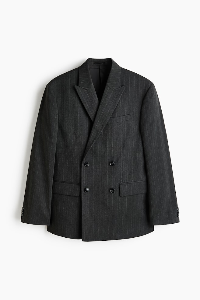 A dark gray pinstriped double-breasted blazer is facing front, featuring wide peak lapels. It is displaying four black buttons in two rows on the front, two flap pockets at the hip, and one welt pocket on the left chest, with three smaller black buttons on each cuff. - 1