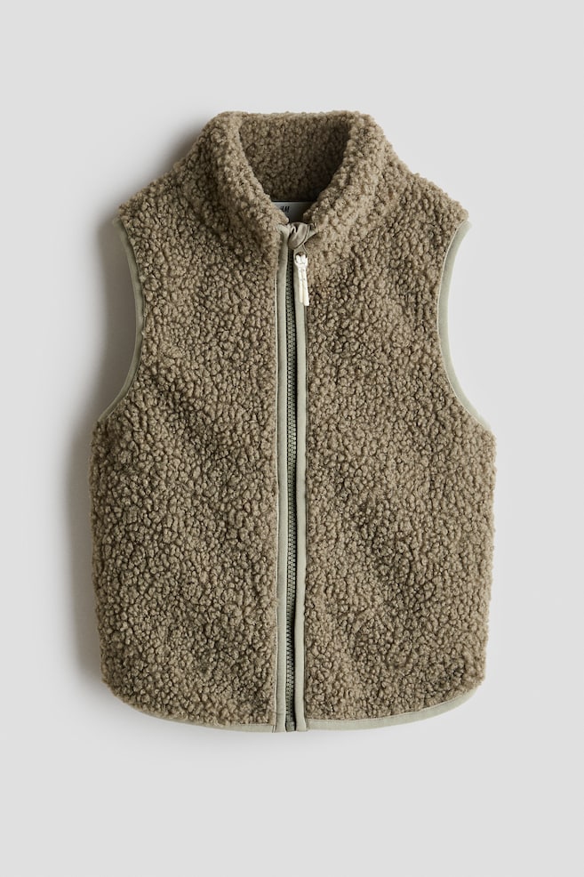 A khaki green teddy fleece vest is showcasing its front, featuring a full zipper closure and a stand-up collar. The vest is adorned with a smooth, lighter green binding along the armholes, hem, and zipper placket. - 1