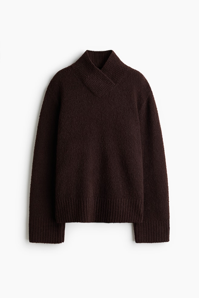 A dark brown knit sweater is shown facing front, showcasing a textured, fuzzy material and a high, ribbed crossover collar. It is featuring long sleeves with wide ribbed cuffs and a matching ribbed hem. - 1