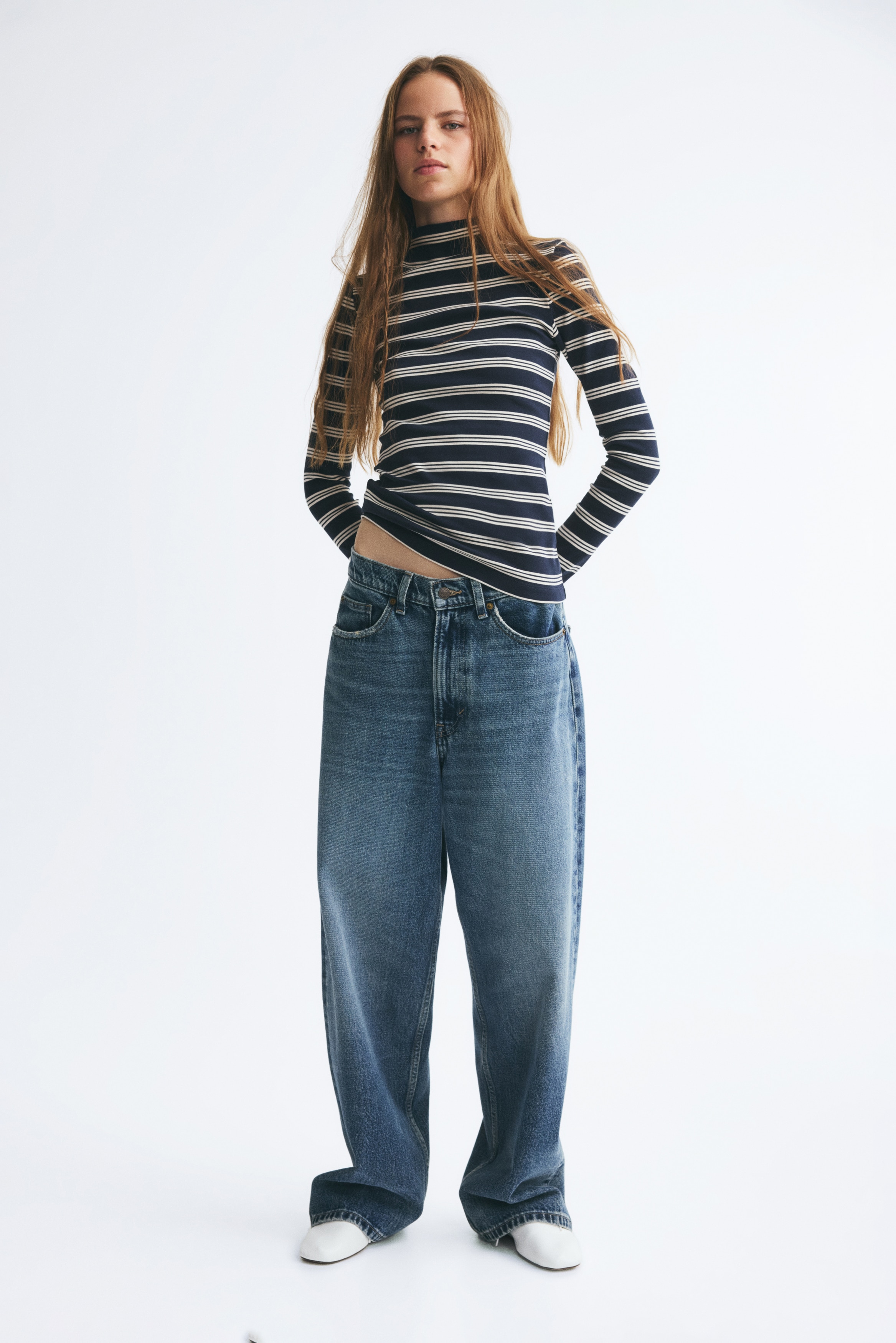 A fitted long-sleeved top features a high mock neck and a horizontal stripe pattern in navy blue and white. The product is shown in a front view with slim-fitting sleeves and a straight hem.