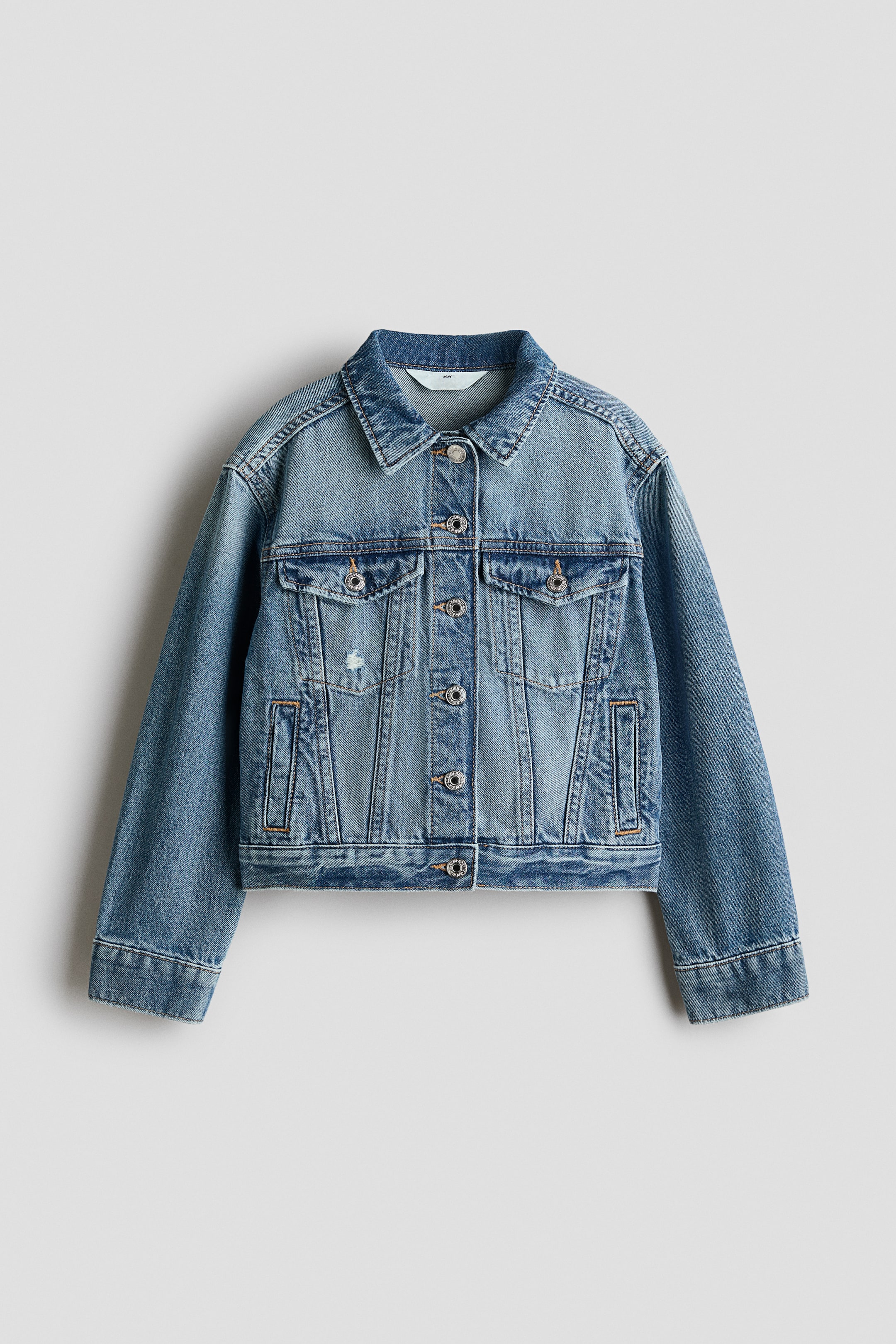 Größeres Bild anzeigen: Die Jacke aus Baumwoll-Denim ist von vorne zu sehen und verfügt über einen Kragen sowie Knöpfe an der Vorderseite, zusammen mit einer Passe vorne. Sie zeigt überschnittene Schultern, lange Ärmel mit Knöpfen an den Manschetten, Leistentaschen vorne, Brusttaschen mit Patte und Knopf sowie einen verstellbaren Riegel mit Knöpfen an jeder Seite des Saums.
