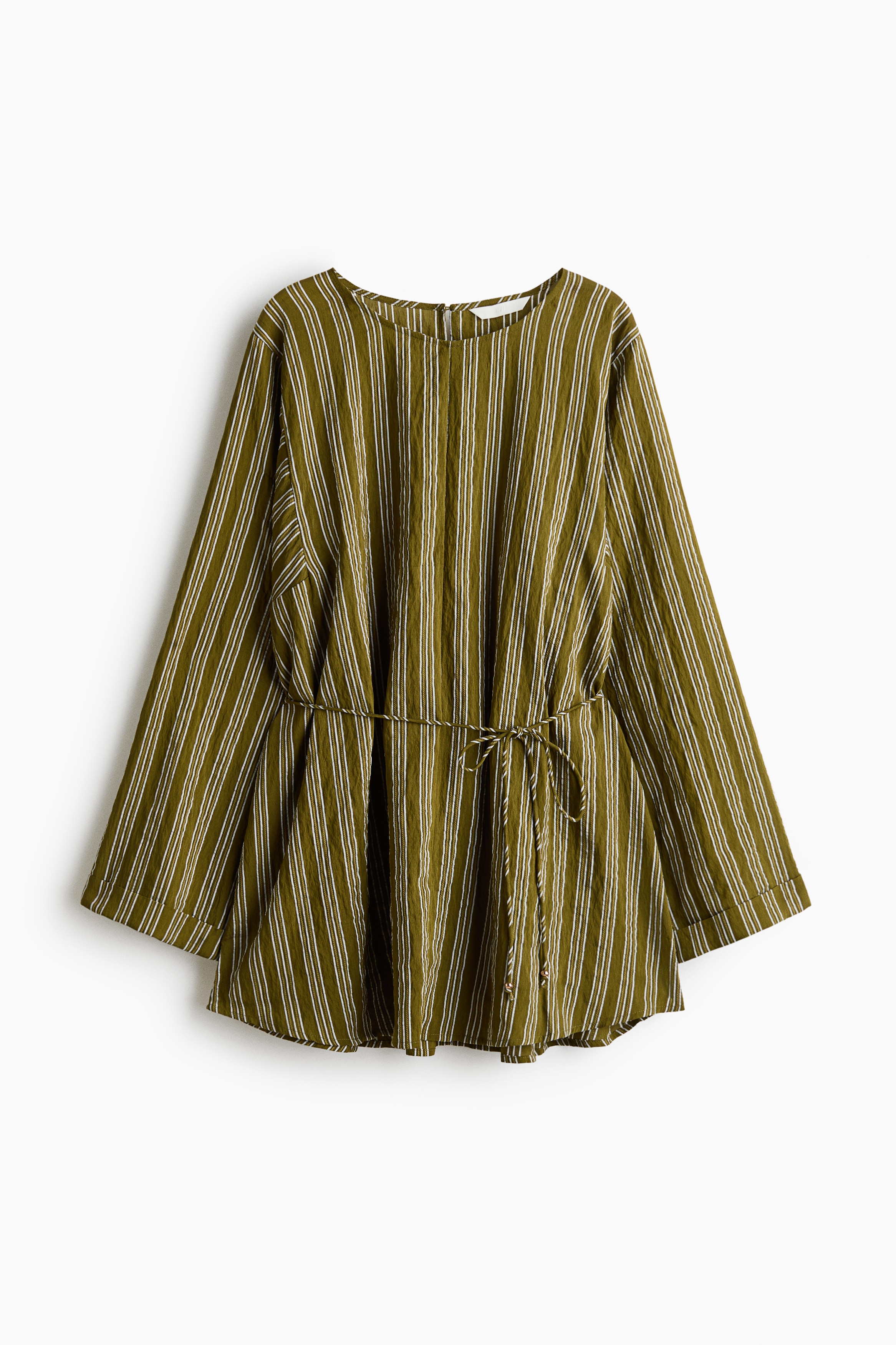 An oversized blouse in a green and white striped textured weave is being worn by the model. The blouse features a round neckline, long sleeves with turn-up cuffs, and a narrow tie belt at the waist, paired with matching striped trousers.
