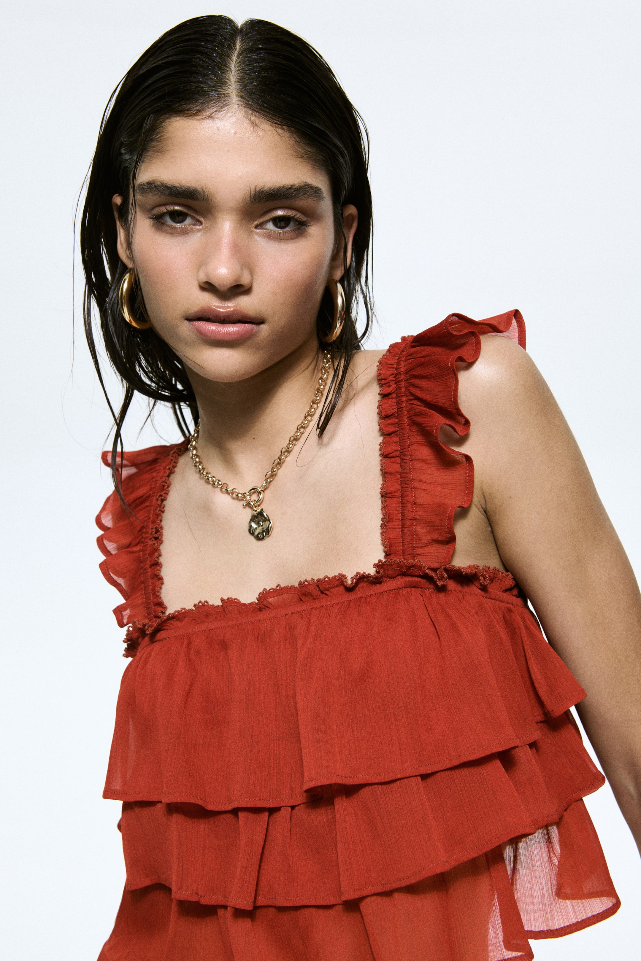 View larger image: A gold-toned chain necklace with a pendant is resting on the top's neckline.