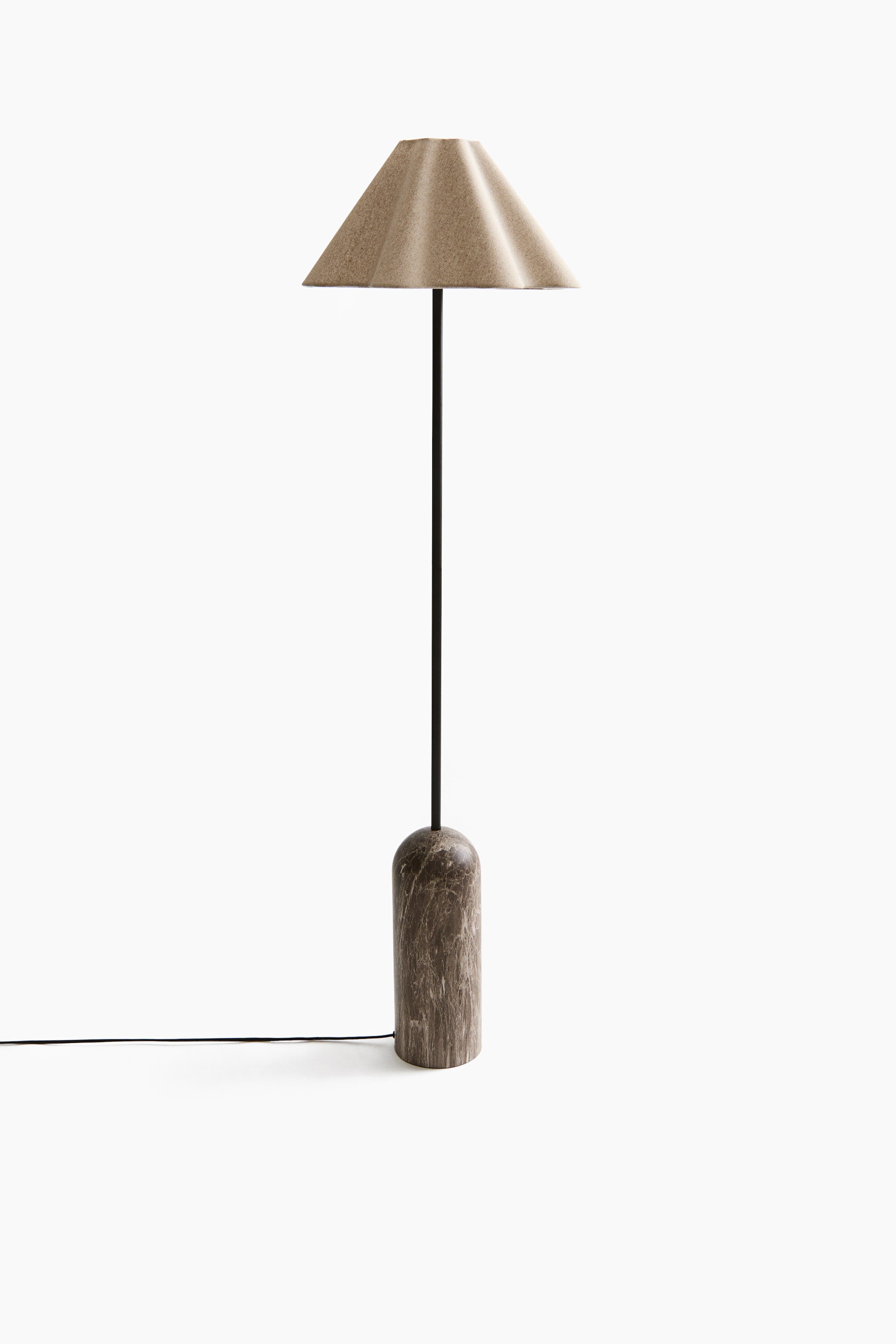Größeres Bild ansehen: Eine Lampe steht aufrecht und verfügt über einen hellbraunen, gefalteten Kegelschirm. Ein dünner schwarzer Stiel verbindet den Schirm mit einem dunkelbraunen, zylindrischen Marmorsockel mit abgerundeten Kanten, von dem ein schwarzes Stromkabel ausgeht.